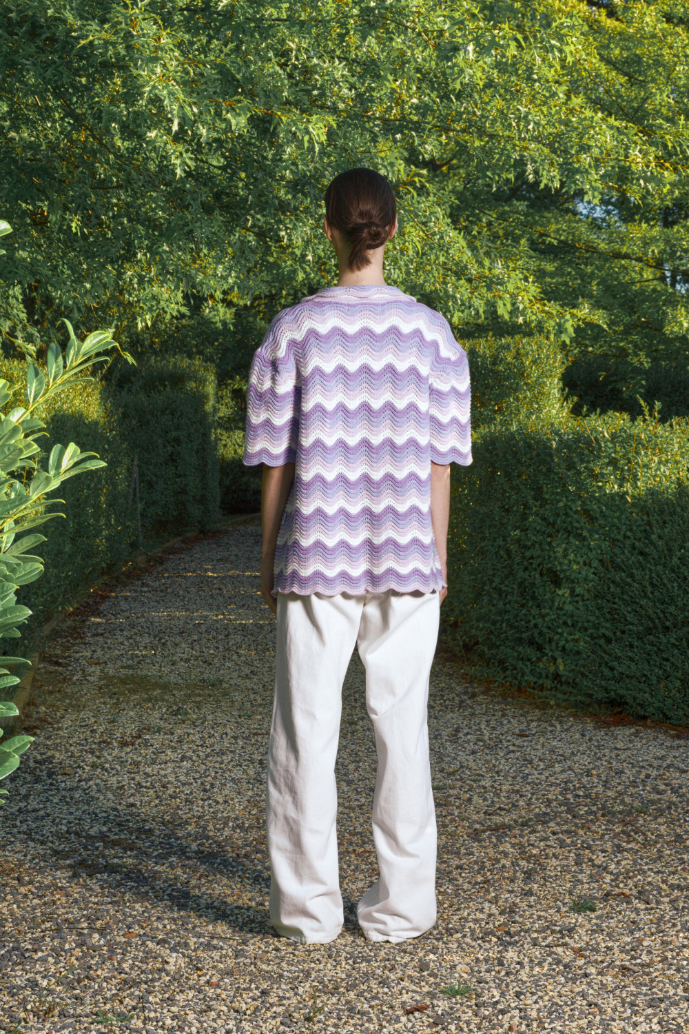 Person wearing a purple and white patterned shirt standing in a garden