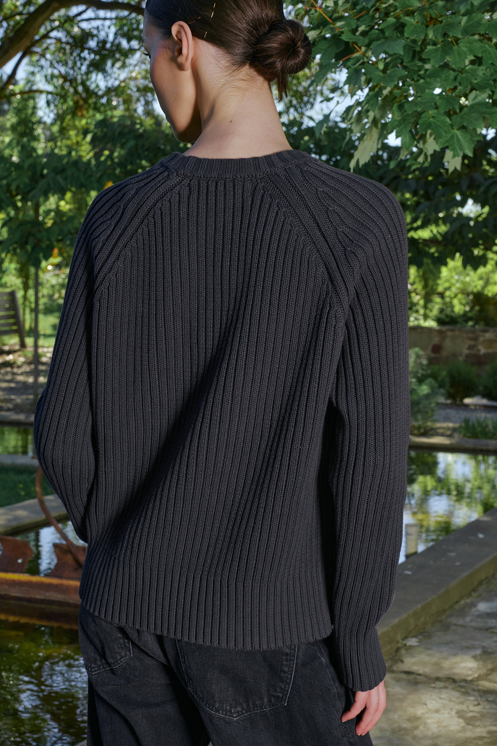 Back view of model wearing a black ribbed knit sweater.