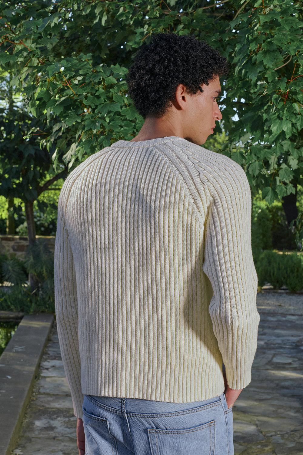 Close up back view for a model wearing a cream ribbed knit sweater.