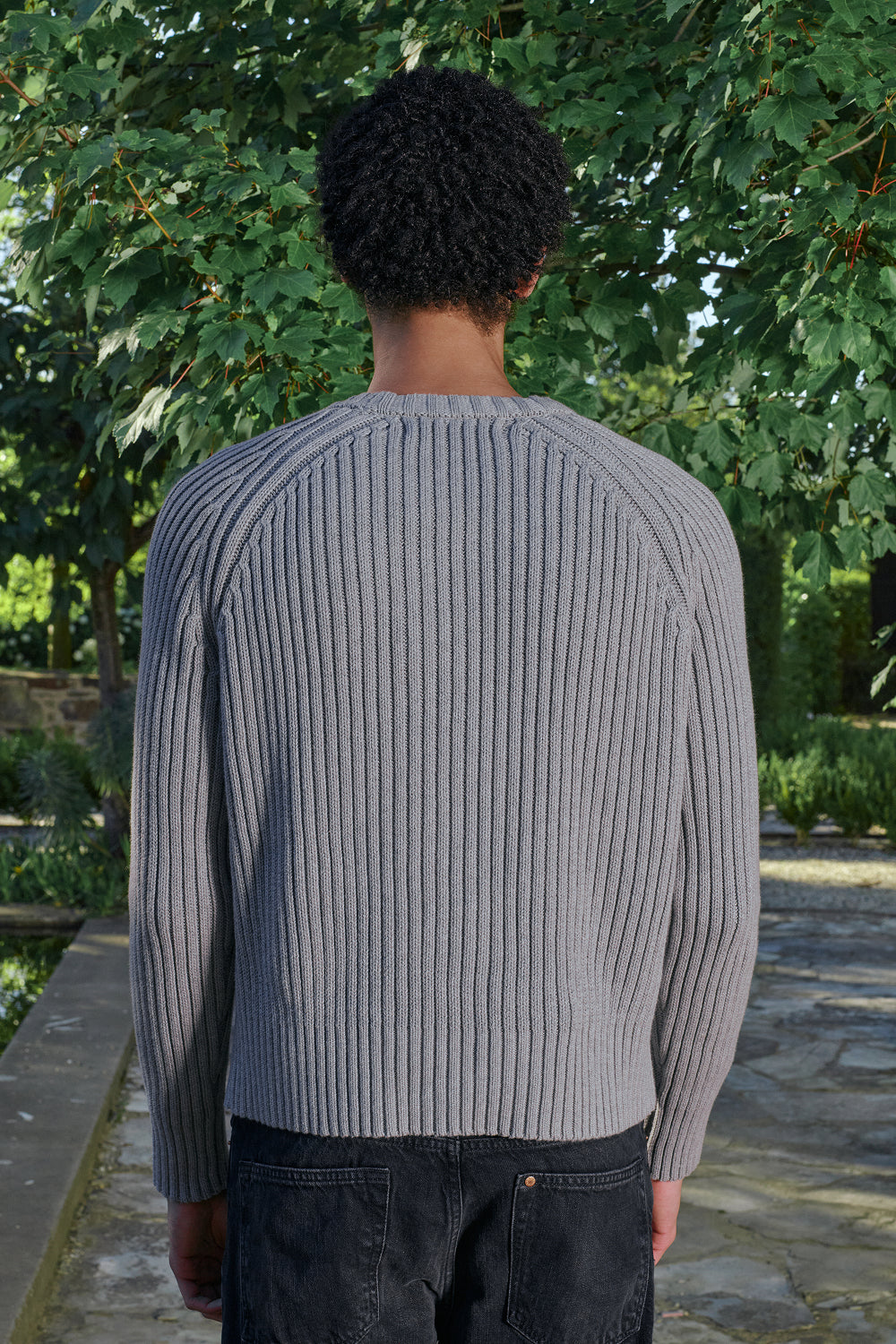 Close up back view for a model wearing a grey ribbed knit sweater.