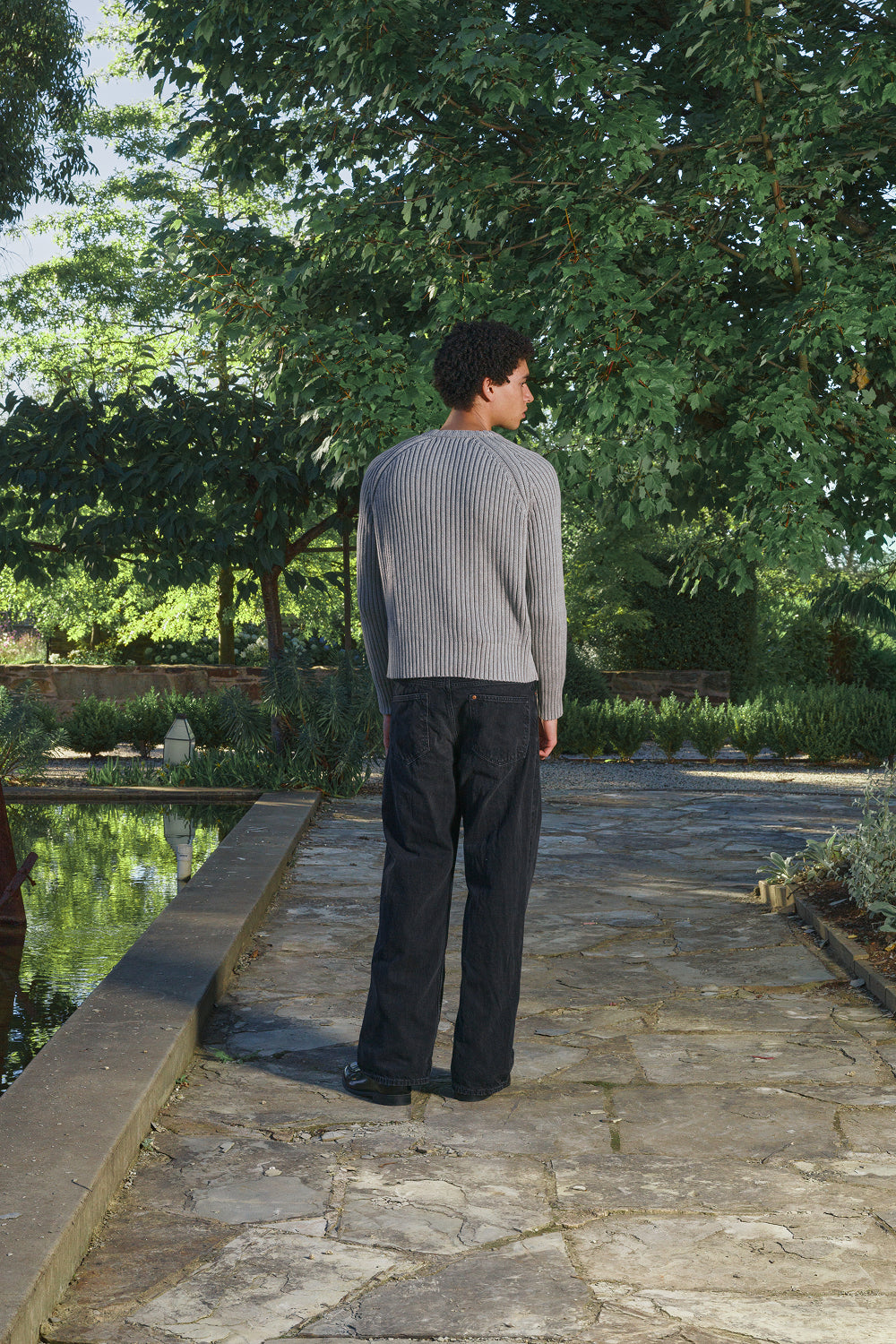 Back view for a model wearing a grey ribbed knit sweater with a black jeans.