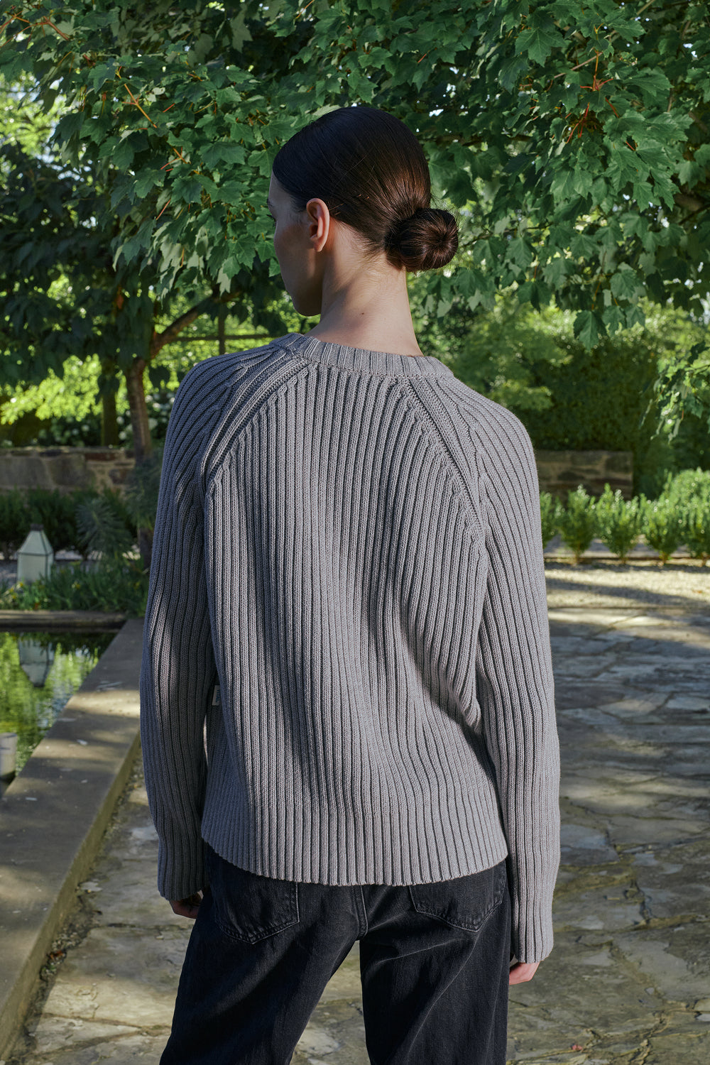 Close up back view for a model wearing a grey ribbed knit sweater.