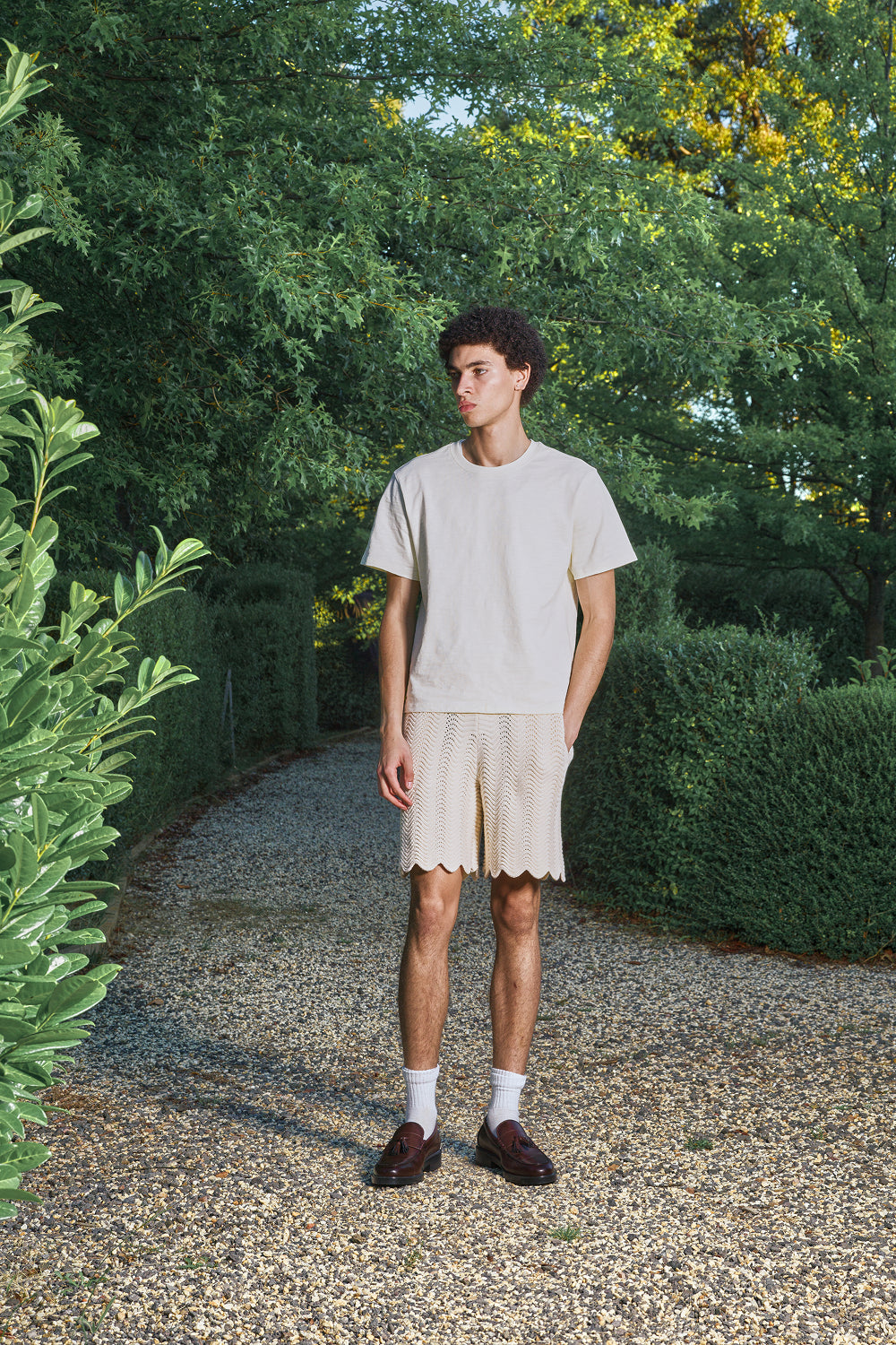 Man wearing an ivory shale stitch shorts standing outdoors.