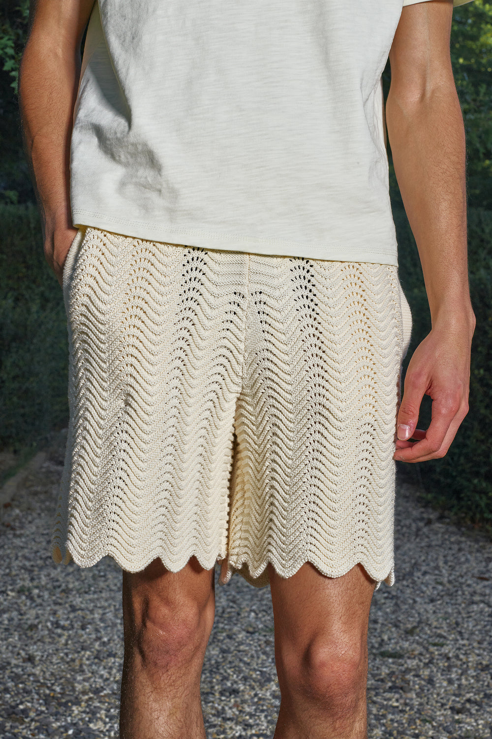 Close-up of model wearing ivory shale stitch knit shorts.