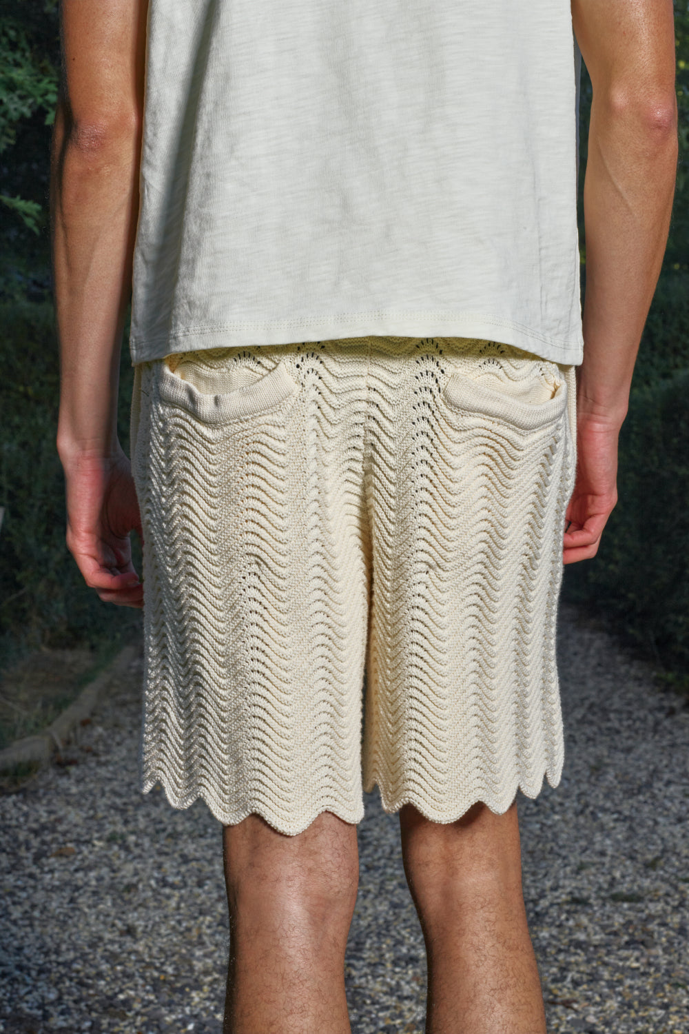 Close-up back view of model wearing white shale stitch knit shorts with back pockets.