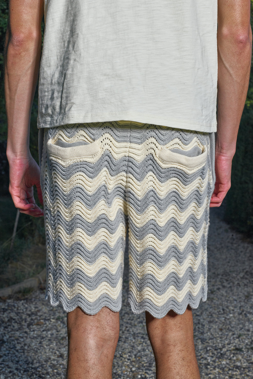 Close-up back view of model wearing grey and white shale stitch knit shorts with back pockets.