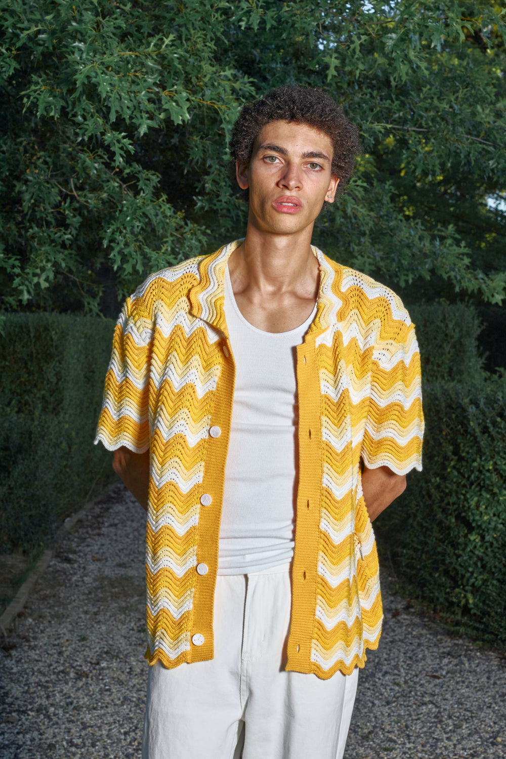 Model wearing a yellow and white shale stitch knit shirt over a white top,