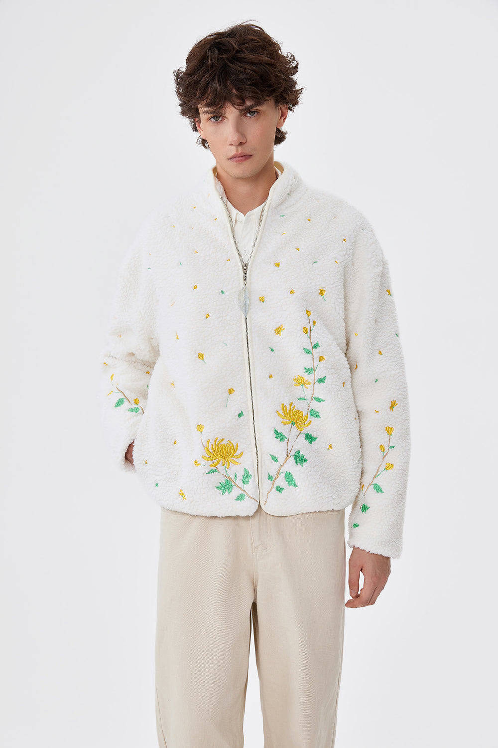 Person wearing a white floral embroidered jacket on a white background