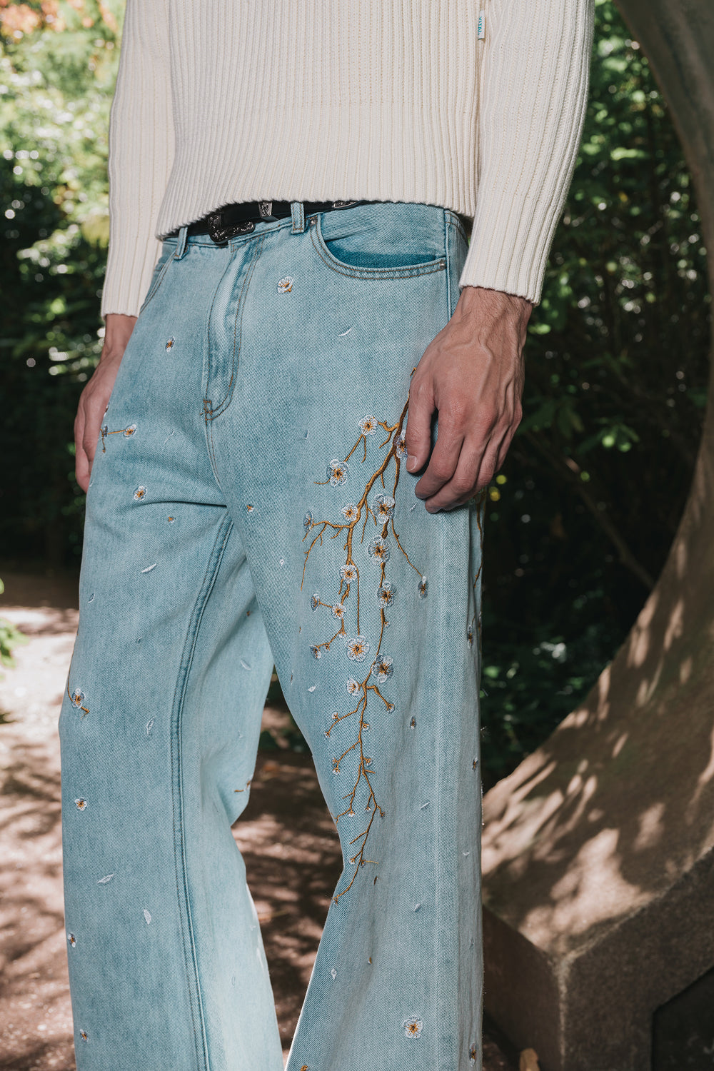 Front close-up of light blue embroidered denim jeans worn by a model.