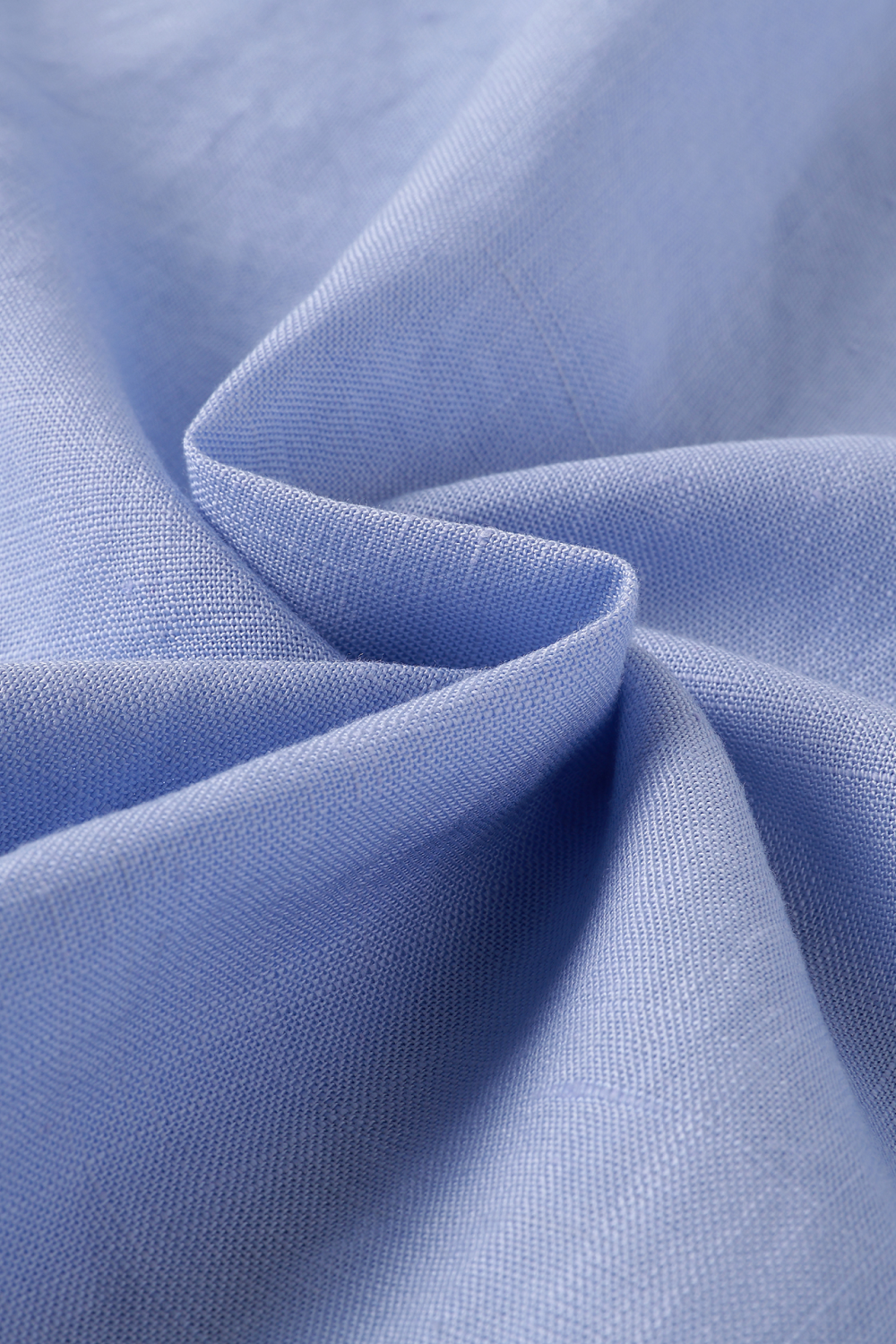 A close-up of light blue fabric with soft folds and a visible texture.
