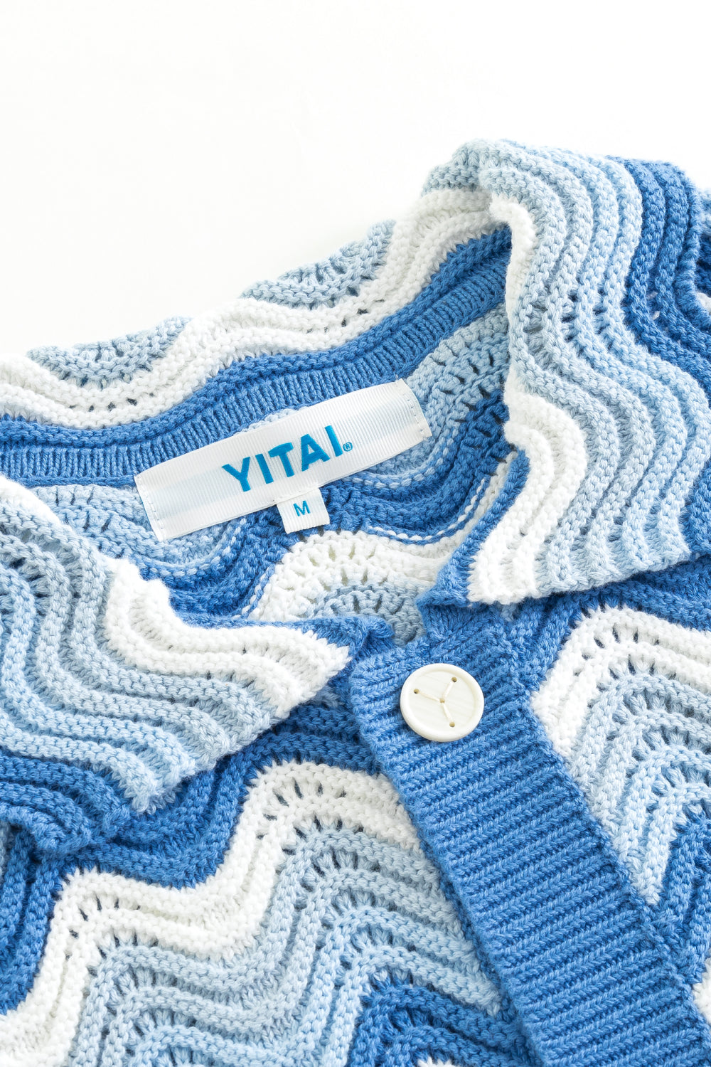Close-up of a blue and white shale stitch knit shirt with a collared neckline, front buttons, textured knit placket, and YITAI label.