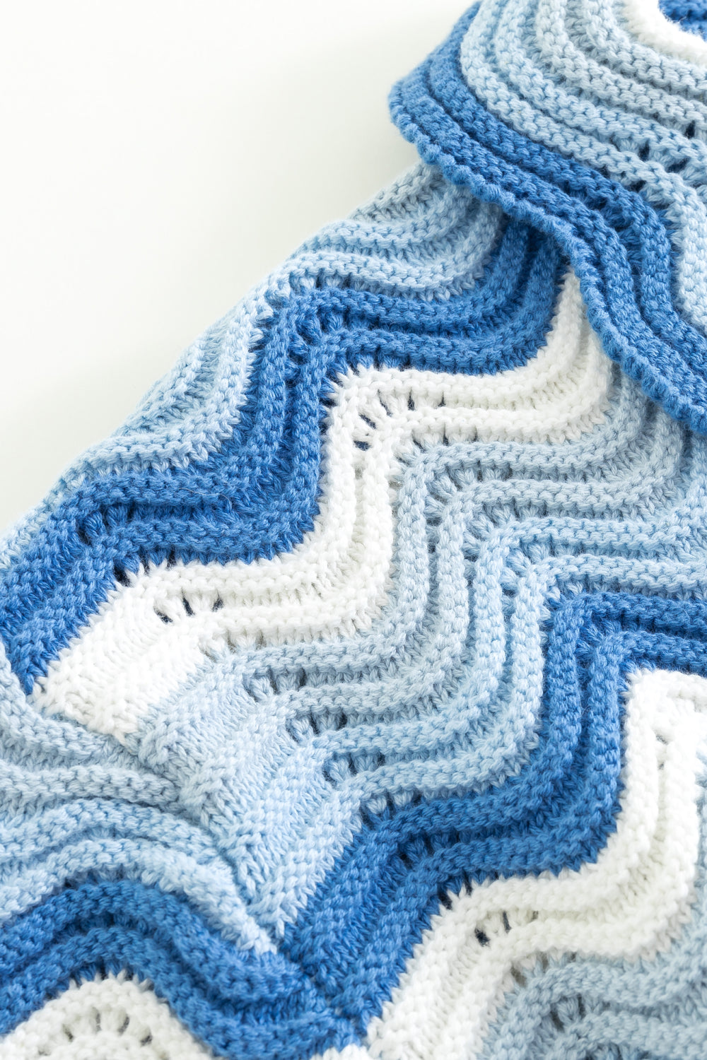Close-up of the shoulder of a blue and white shale stitch knit shirt.