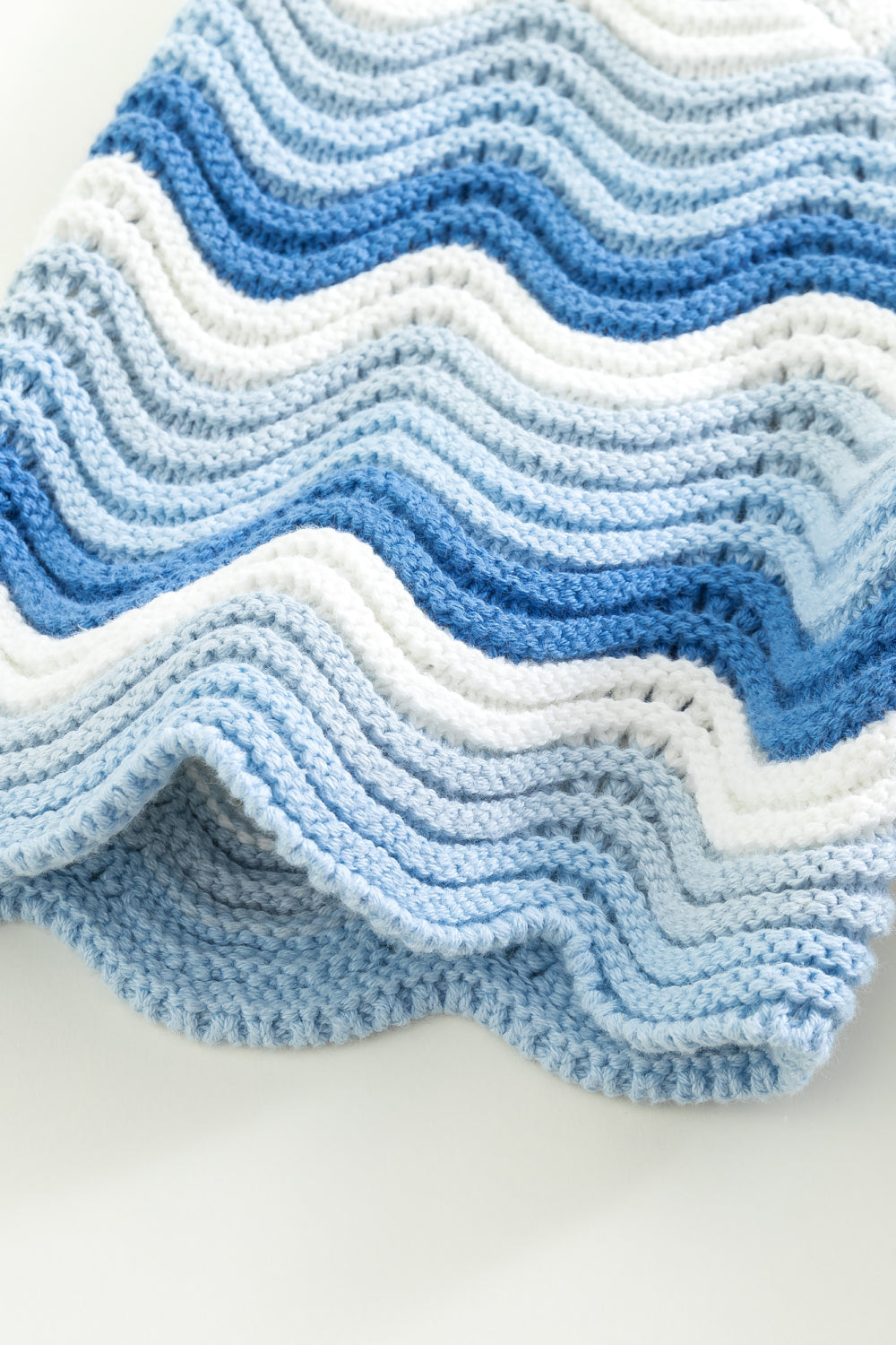 Close-up of the sleeve of a blue and white shale stitch knit shirt, showing the scalloped hem finish.