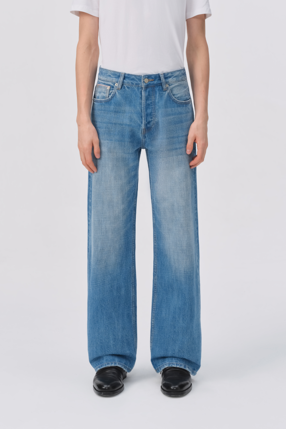 Straight-on view of light-wash straight-leg denim jeans from waist to ankle, worn with black loafers, highlighting the relaxed silhouette.