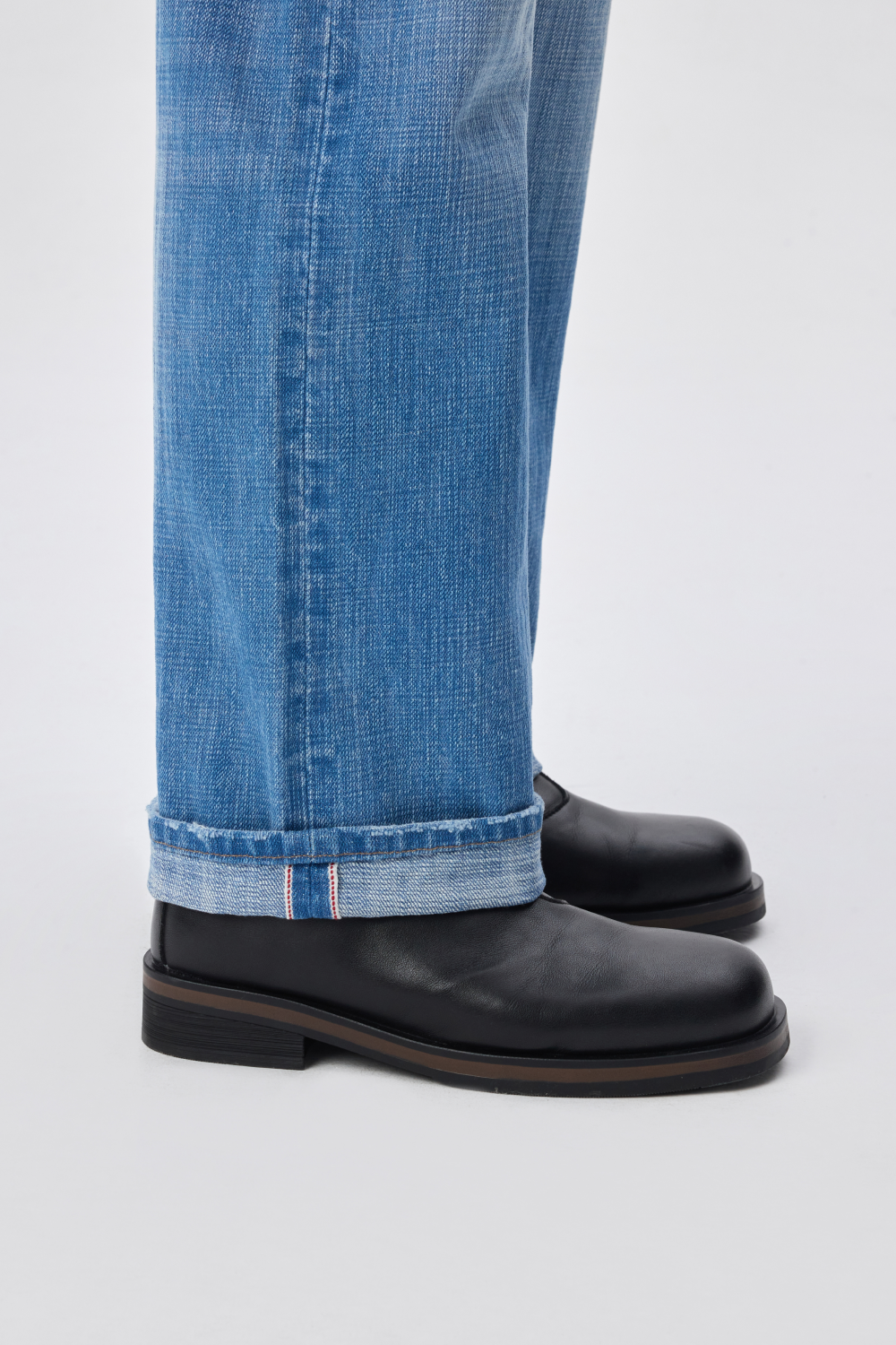 Close-up of light-wash denim hem with red selvedge edge.