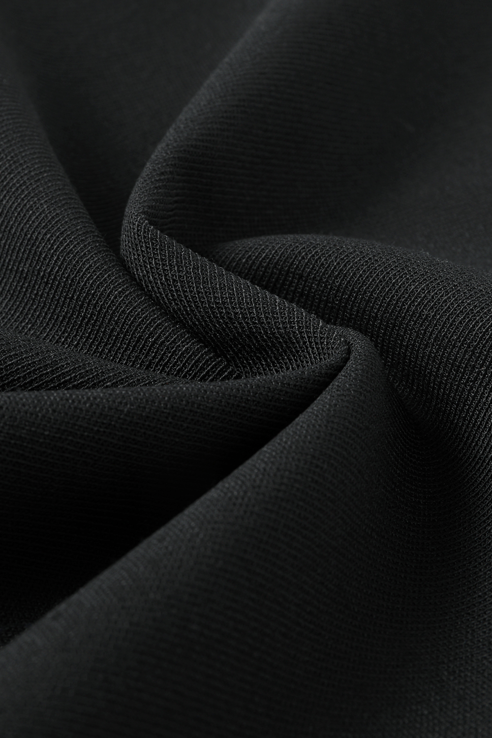 Close-up of black wool trouser fabric, showing its textured weave and soft folds.