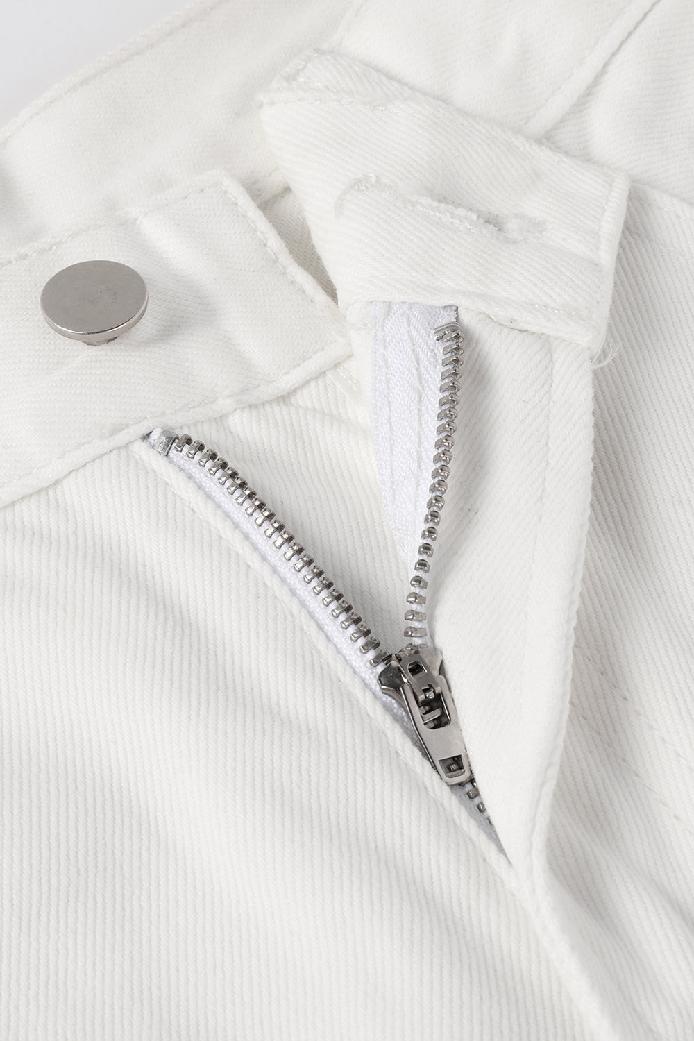 Close-up of white jeans with metal zipper and button closure detail