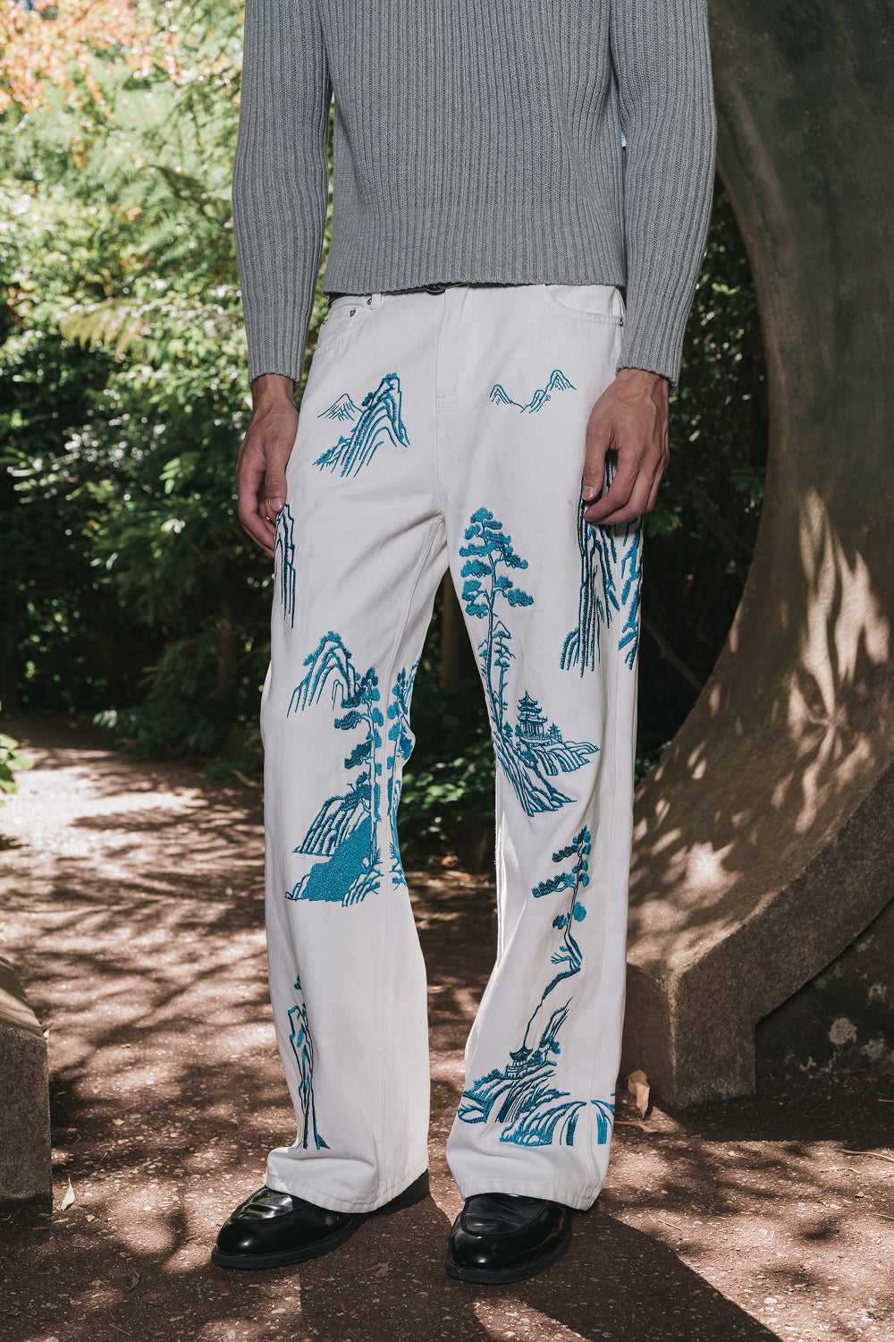 Person wearing white pants with blue tree patterns outdoors