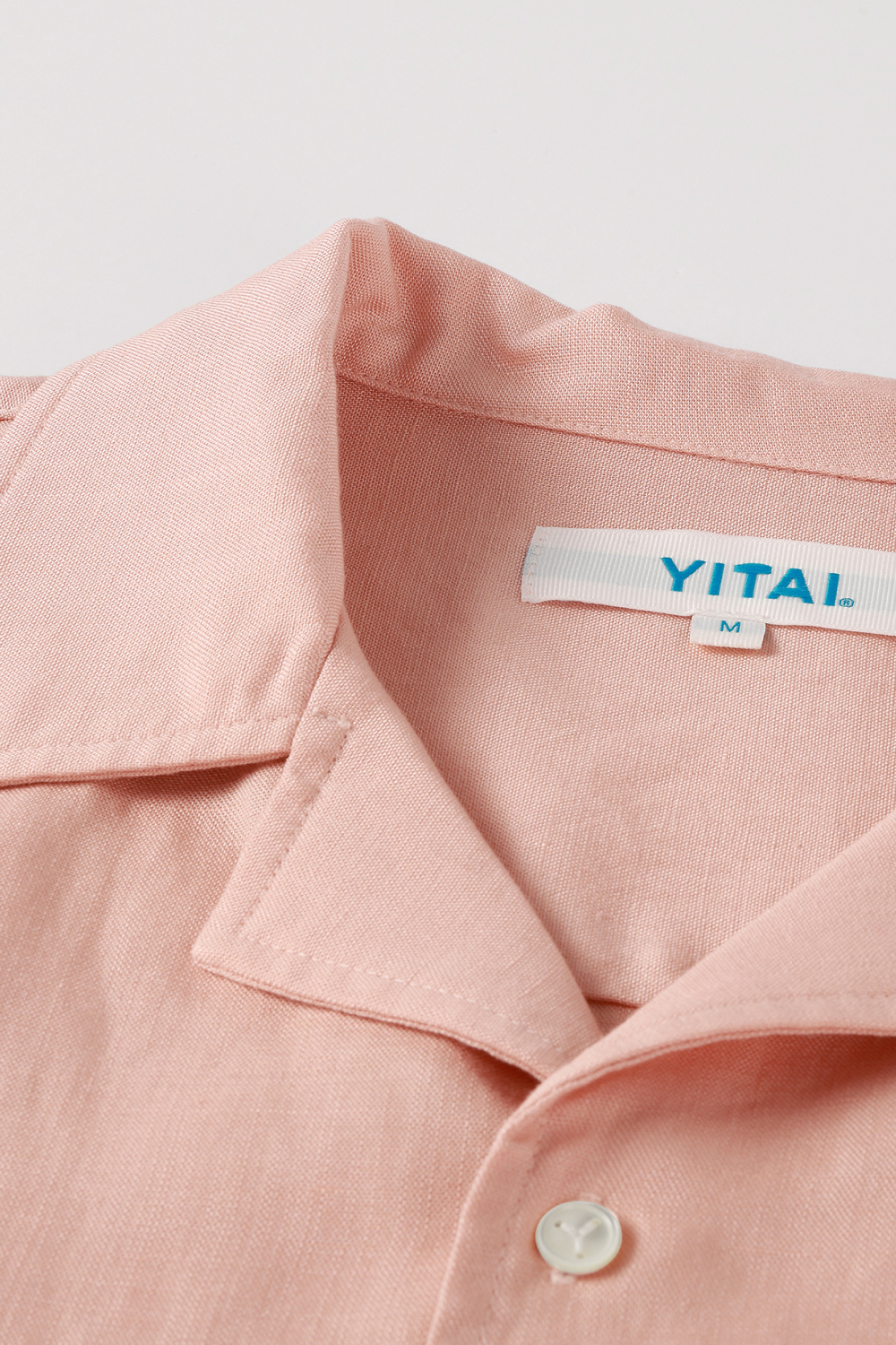 Close-up of a light pink shirt with a camp collar and YITAI neck label.
