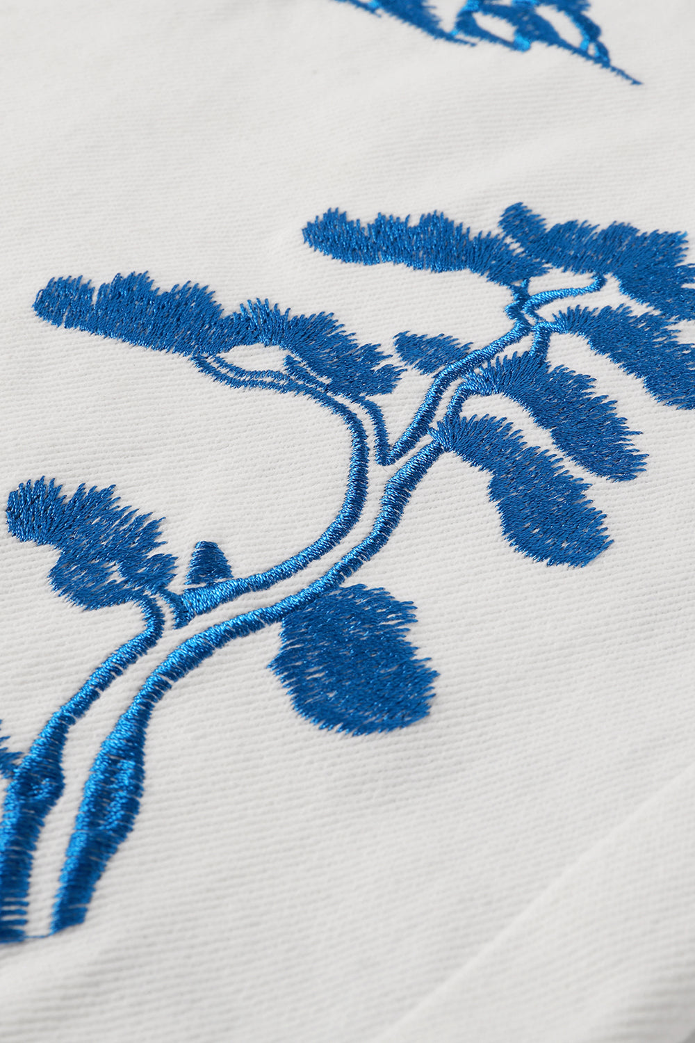 Close-up of blue embroidered floral pattern on a white fabric background