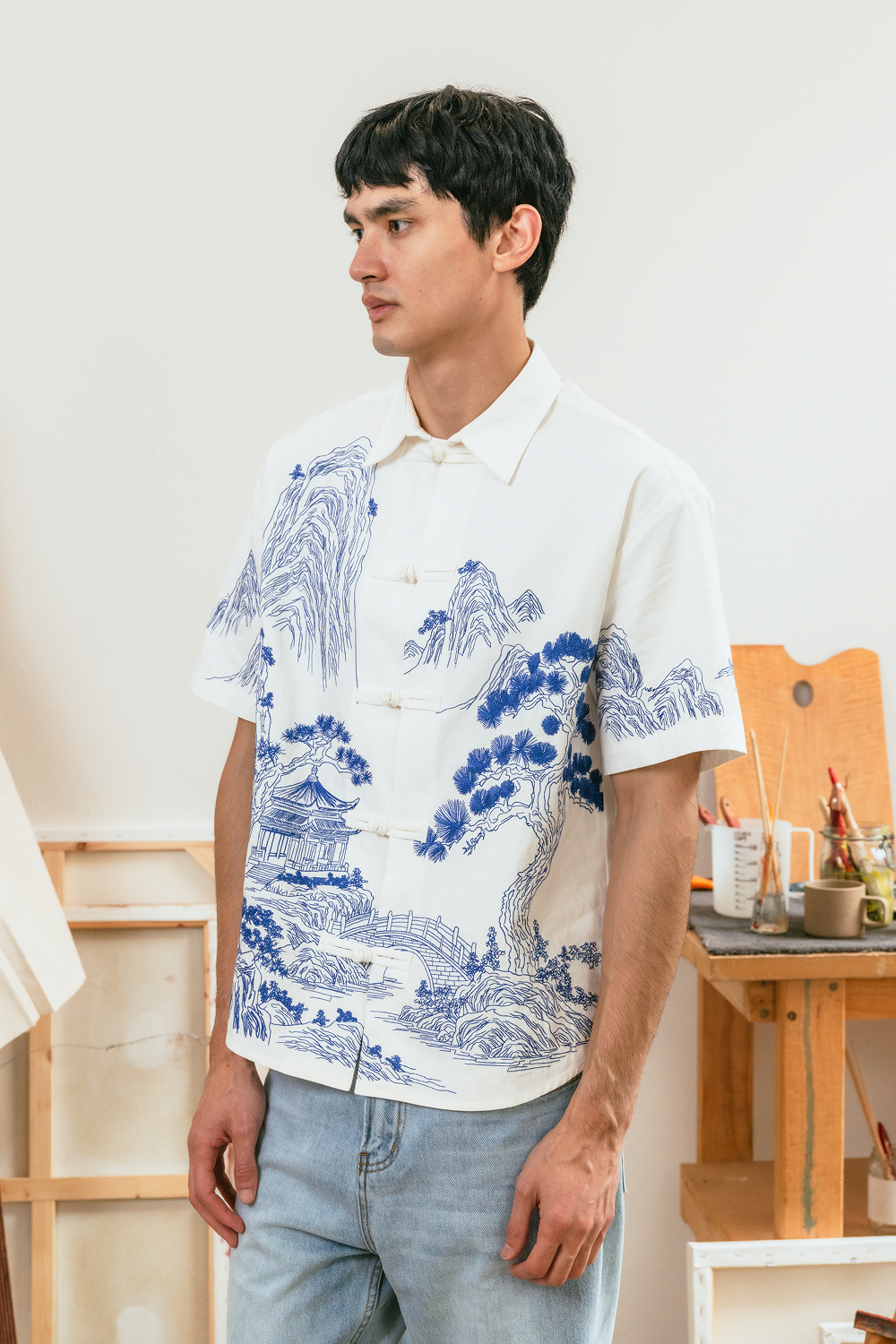 Model wearing a white shirt with traditional blue embroidery.