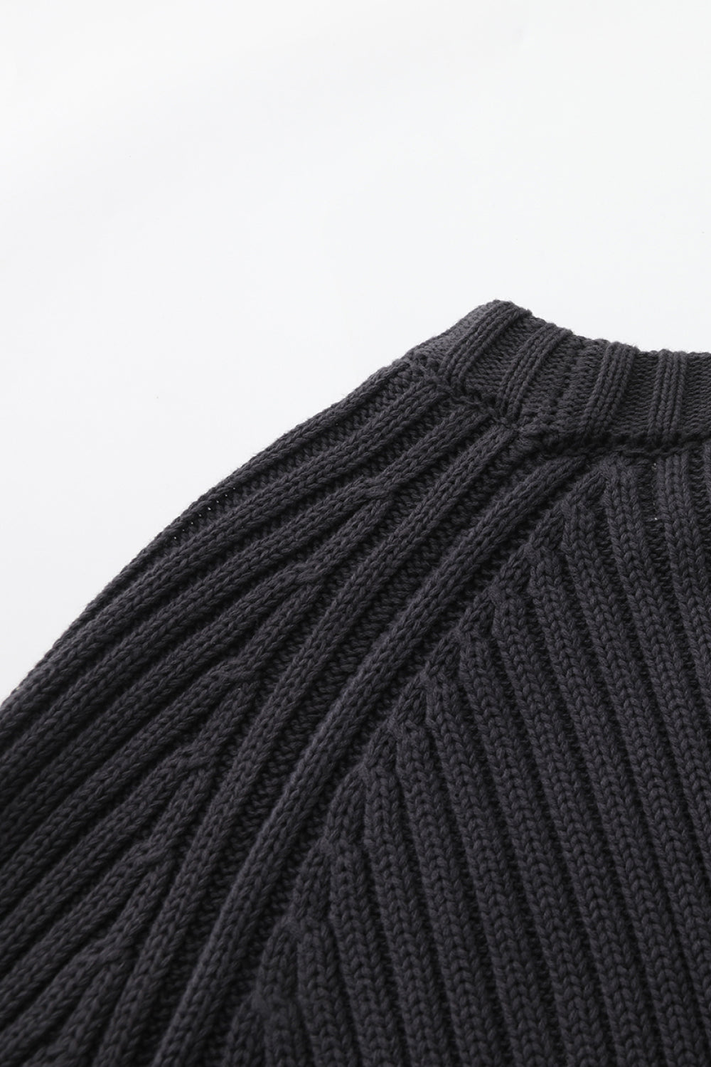 Close-up of a black ribbed knit sweater on a white background