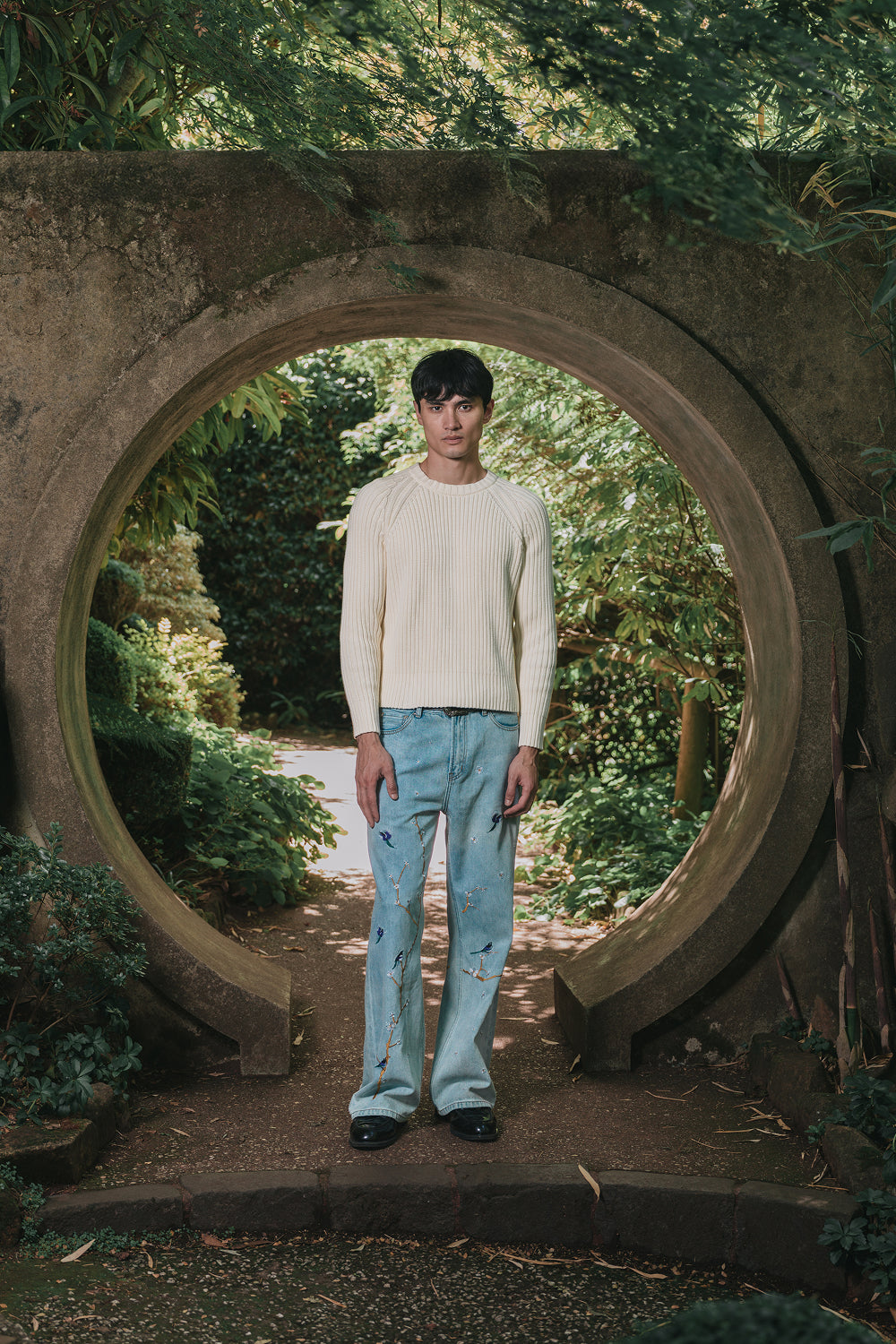 Full front view of model wearing light blue denim jeans with bird and branchs embroidery