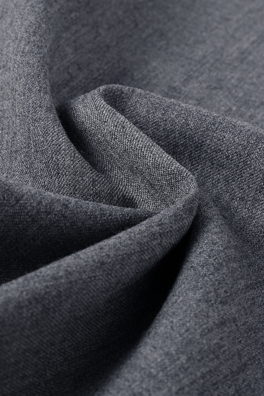Close-up of grey wool trouser fabric, showing its textured weave and soft folds.