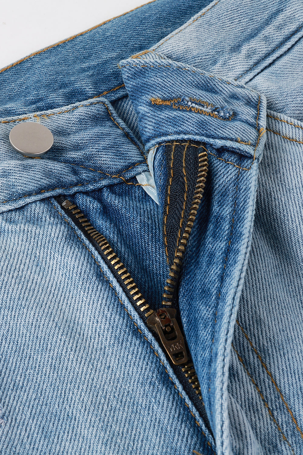 Close-up of zipper and waistband detail on light blue denim jeans