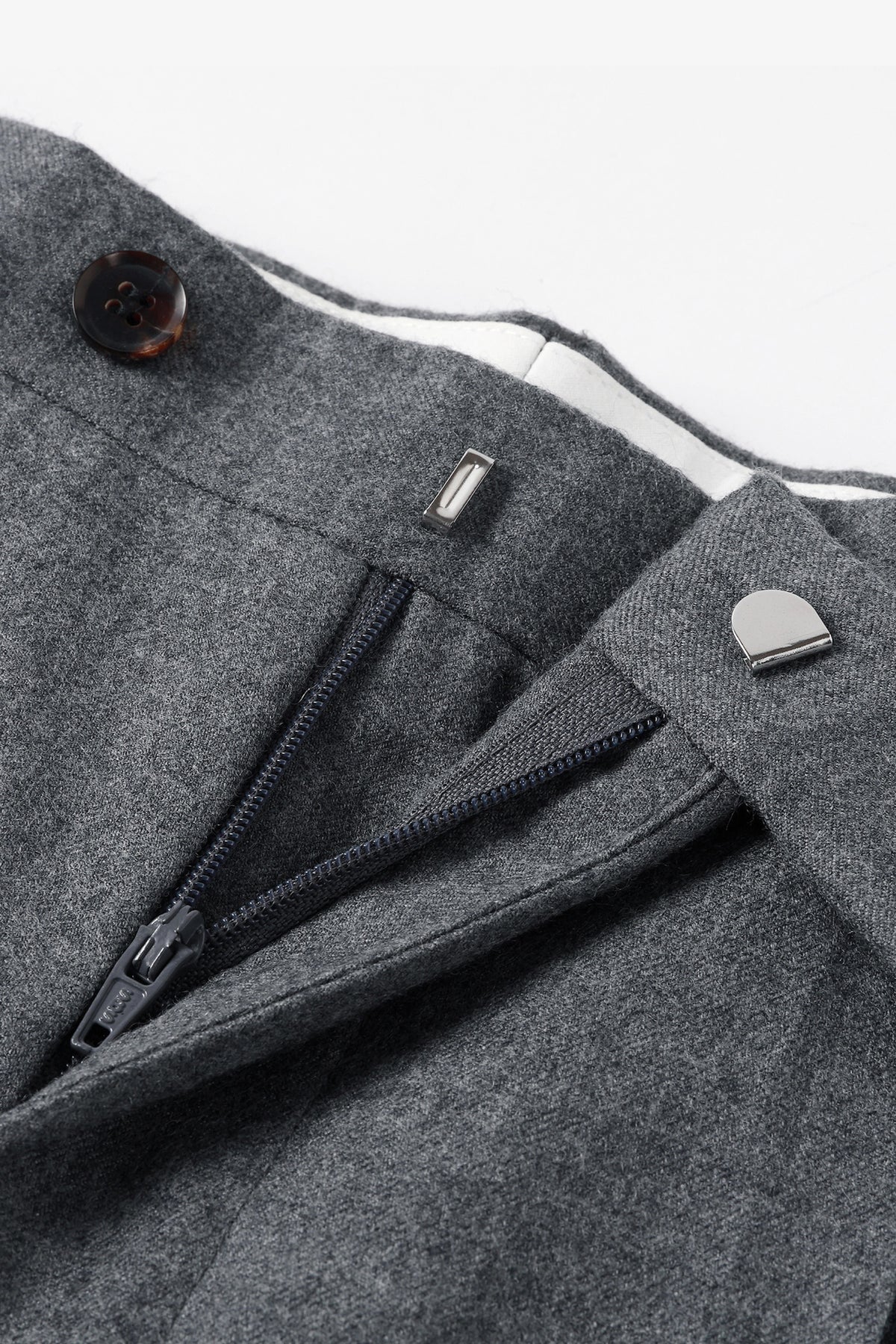 Close-up detail of grey wool trousers fly, zipper, and hook-and-bar closure