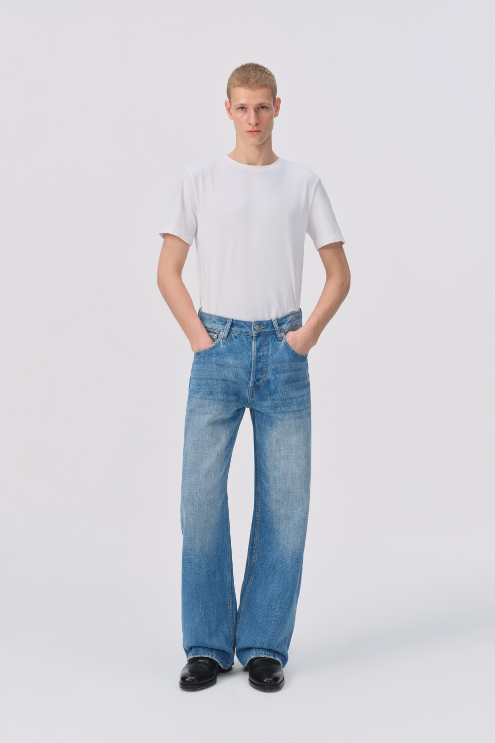 Man wearing a white crew-neck t-shirt with light-wash, straight-leg denim jeans featuring a relaxed fit and visible front pockets.