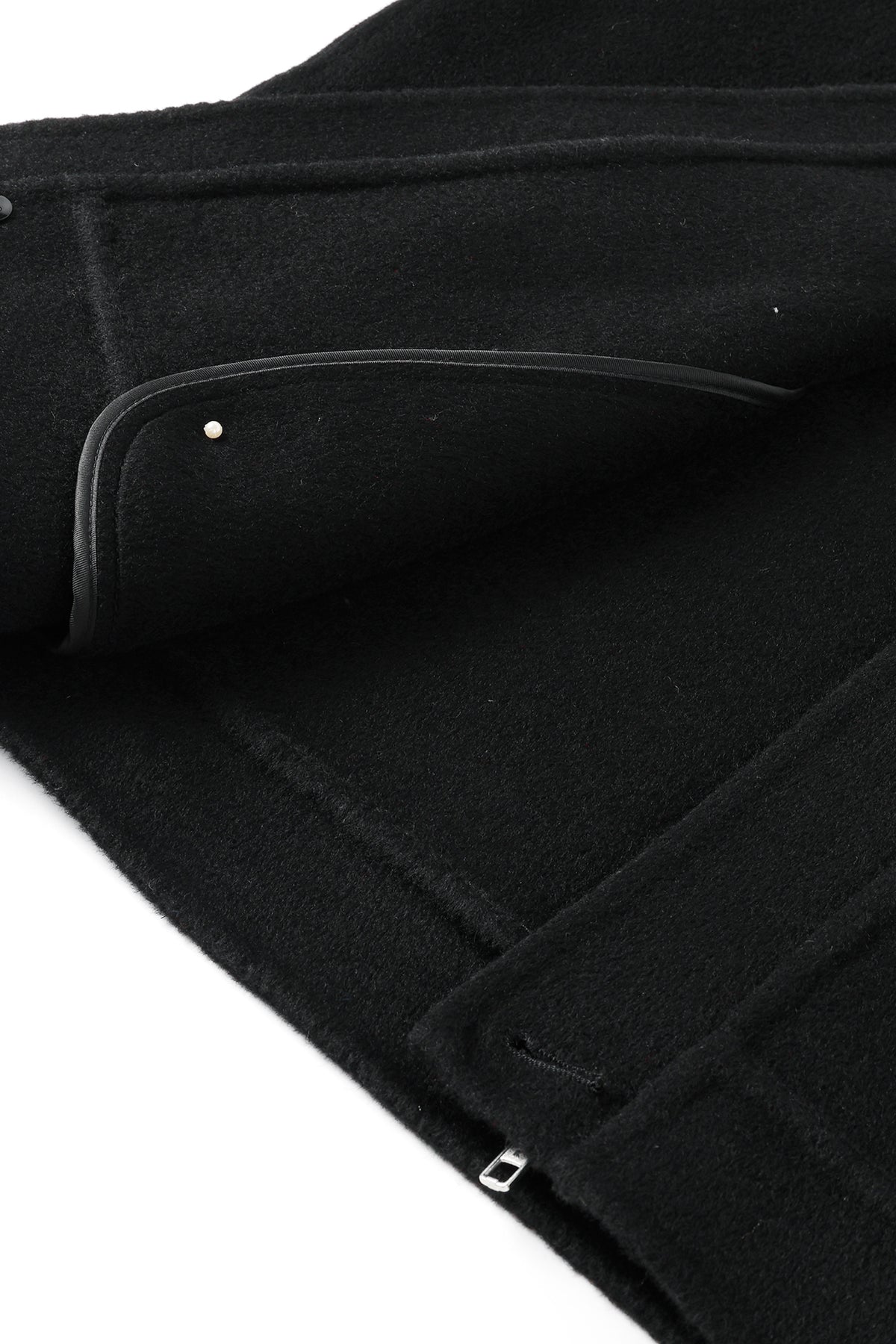 Close-up interior view of the black wool and cashmere jacket, highlighting the unlined textured fabric, a curved inner pocket with black leather trim, and a silver metal stud detail.