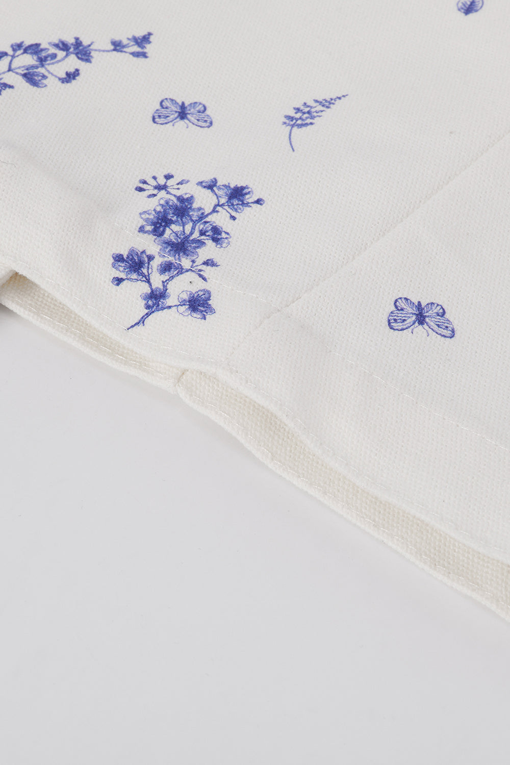White fabric with blue floral embroidery on a white background