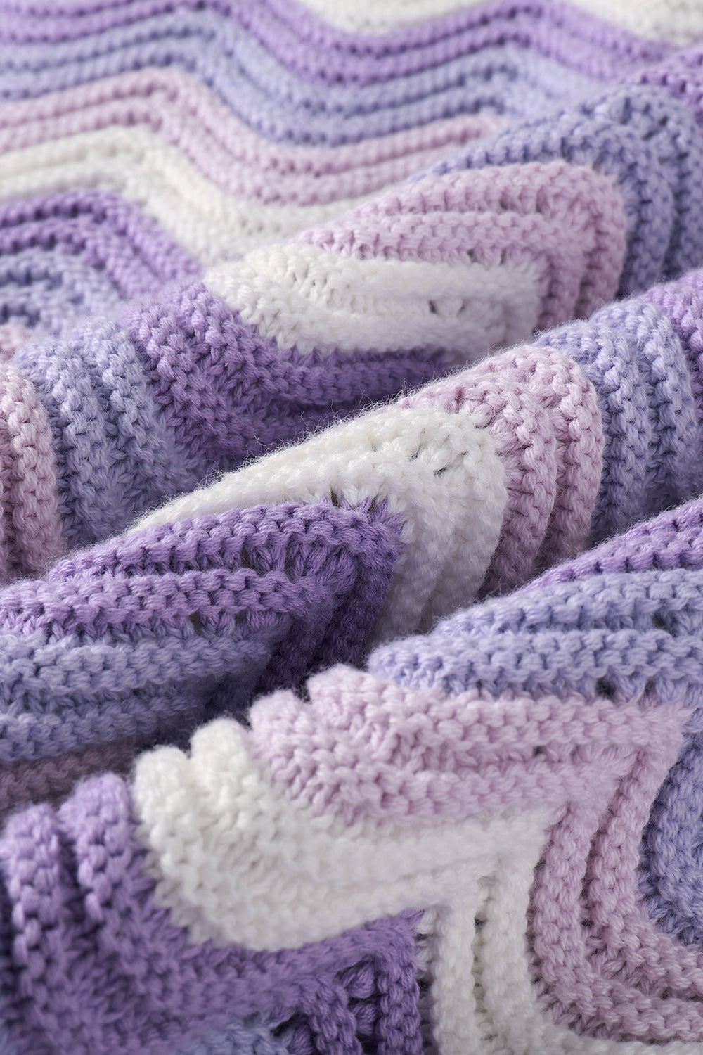 Close-up of a knit shirt with wavy pattern in purple, and white.