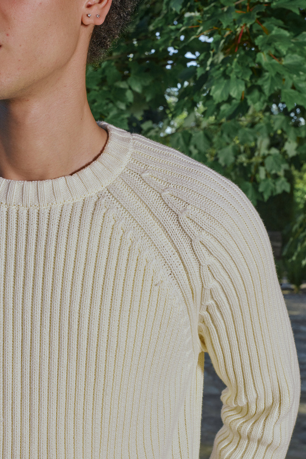 Close-up of cream ribbed knit sweater with raglan sleeve detail.