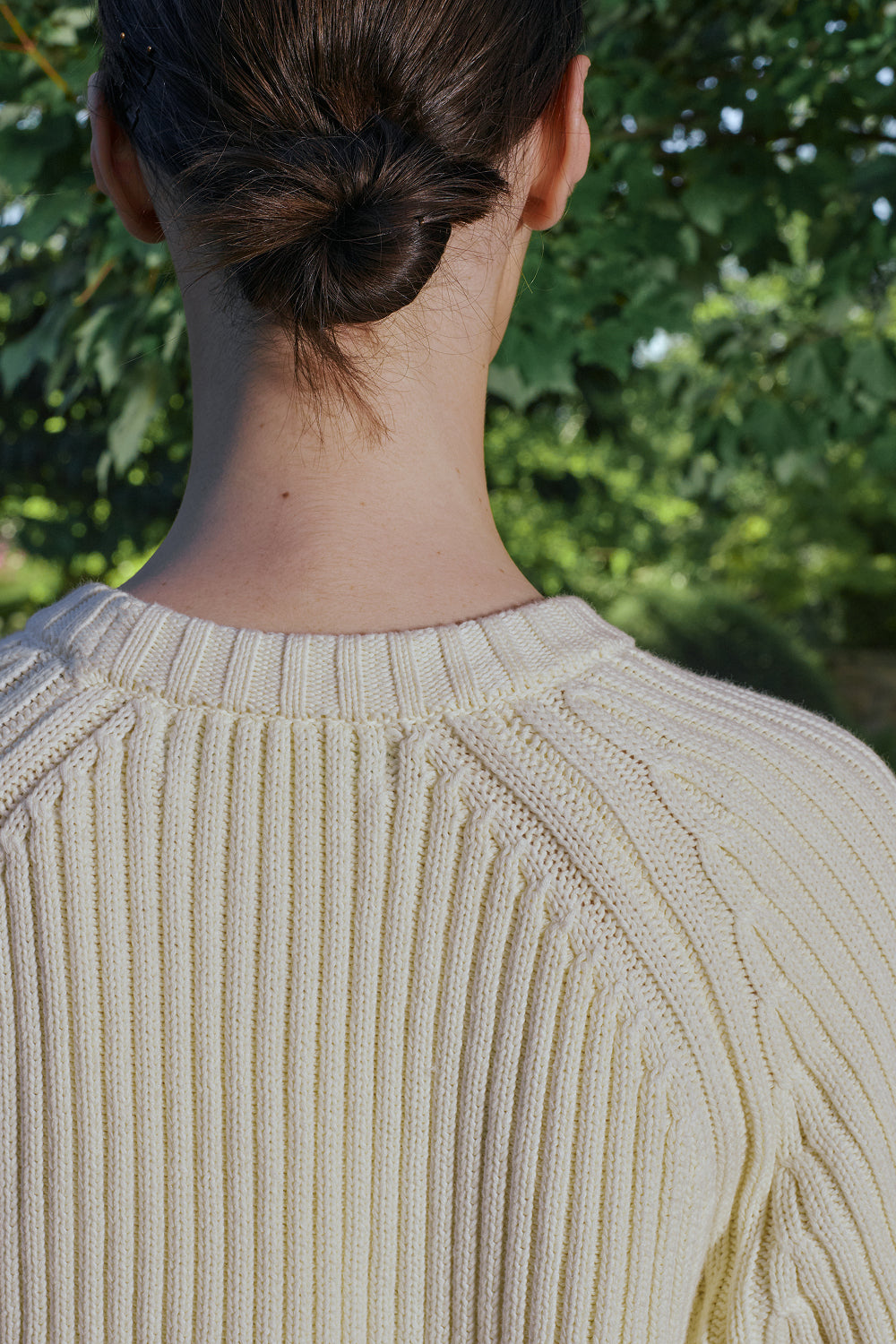 Back view for a model wearing a cream ribbed knit sweater.