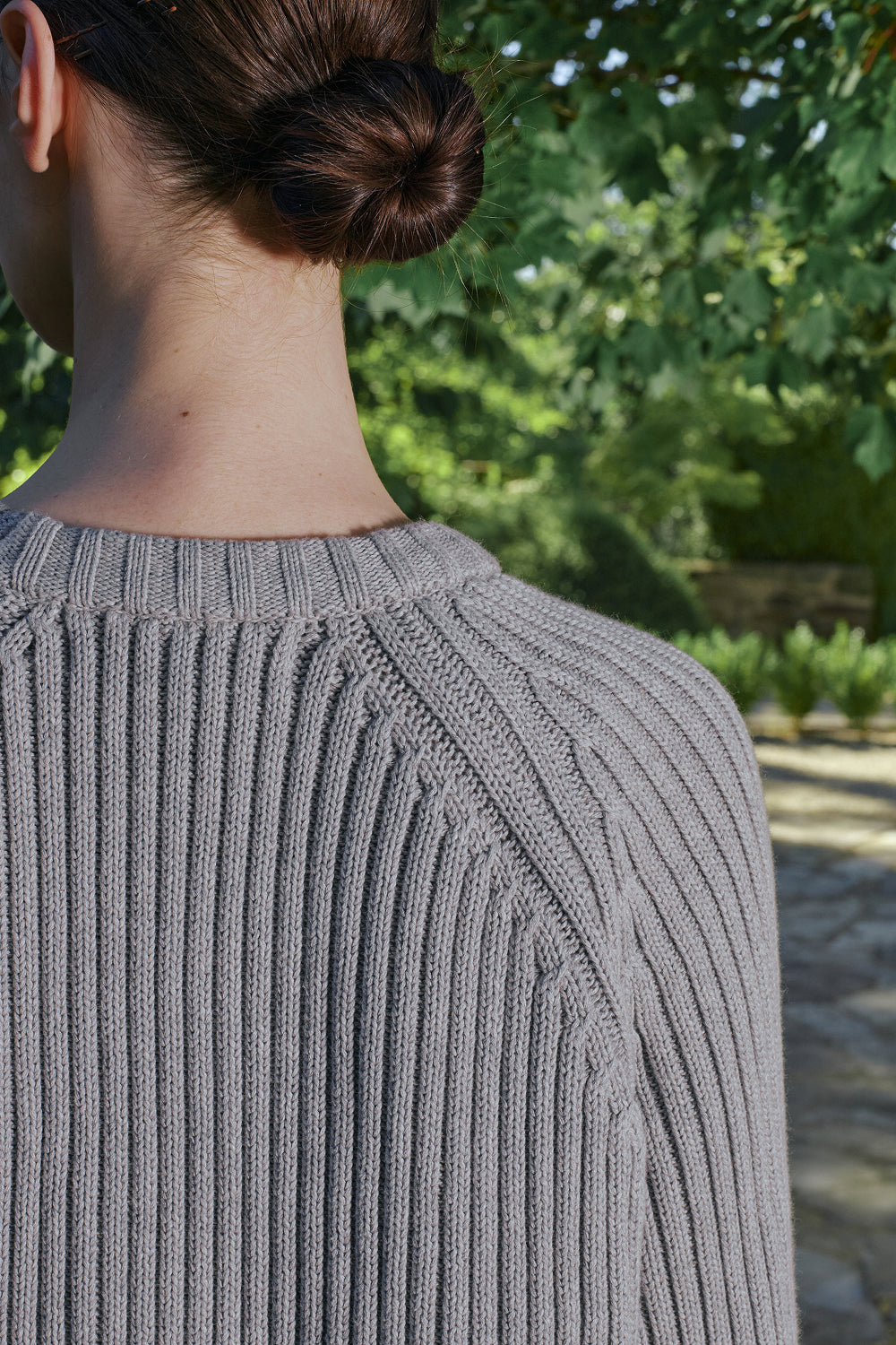 Close-up back view of grey ribbed knit sweater with raglan sleeve detail.