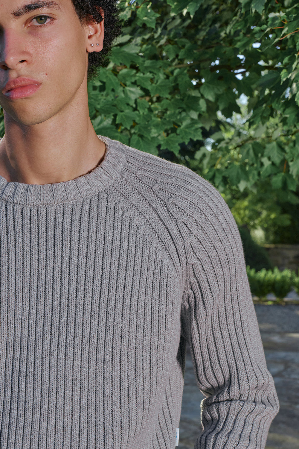 Close-up of grey ribbed knit sweater with raglan sleeve detail.