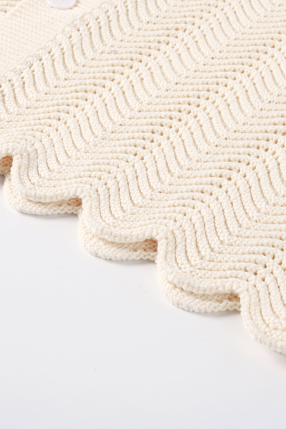 Close-up of ivory shale stitch knit shirt with scalloped hem.
