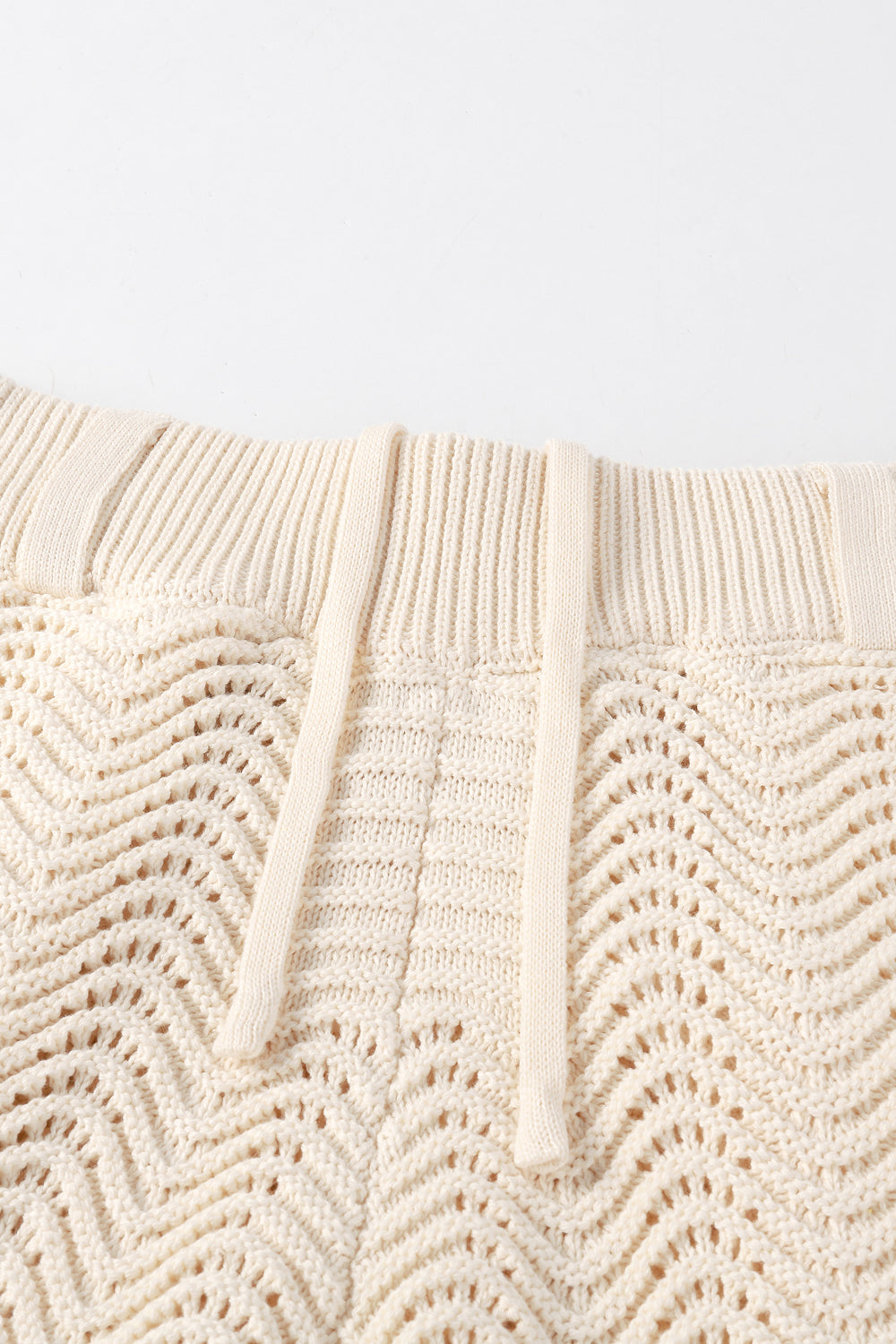 Close-up of ivory shale stitch knit shorts with drawstring waistband.