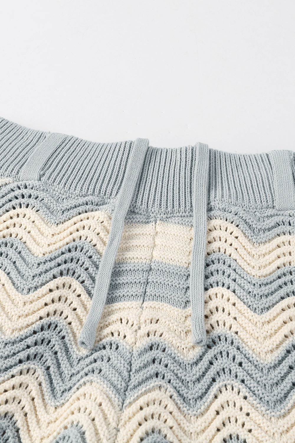 Close-up of grey and white shale stitch knit shorts with drawstring waistband.