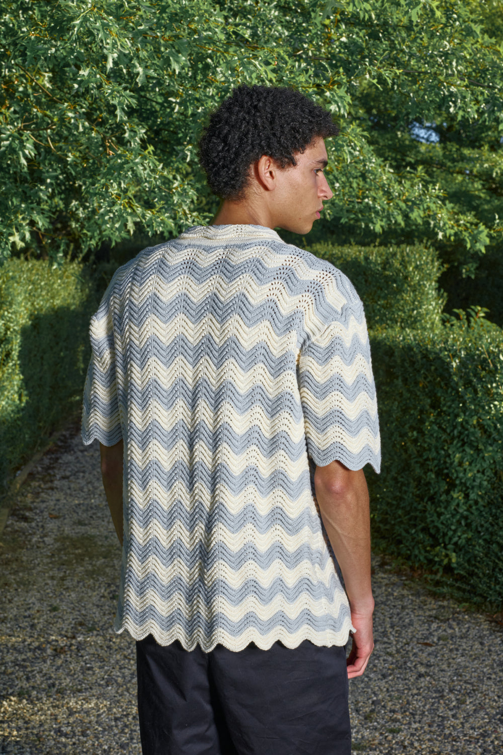 Back view for a male model wearing a grey and cream shale stitch shirt outdoors
