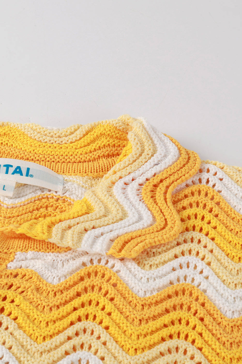 Close-up of yellow and white shale stitch crochet shirt with scalloped collar.