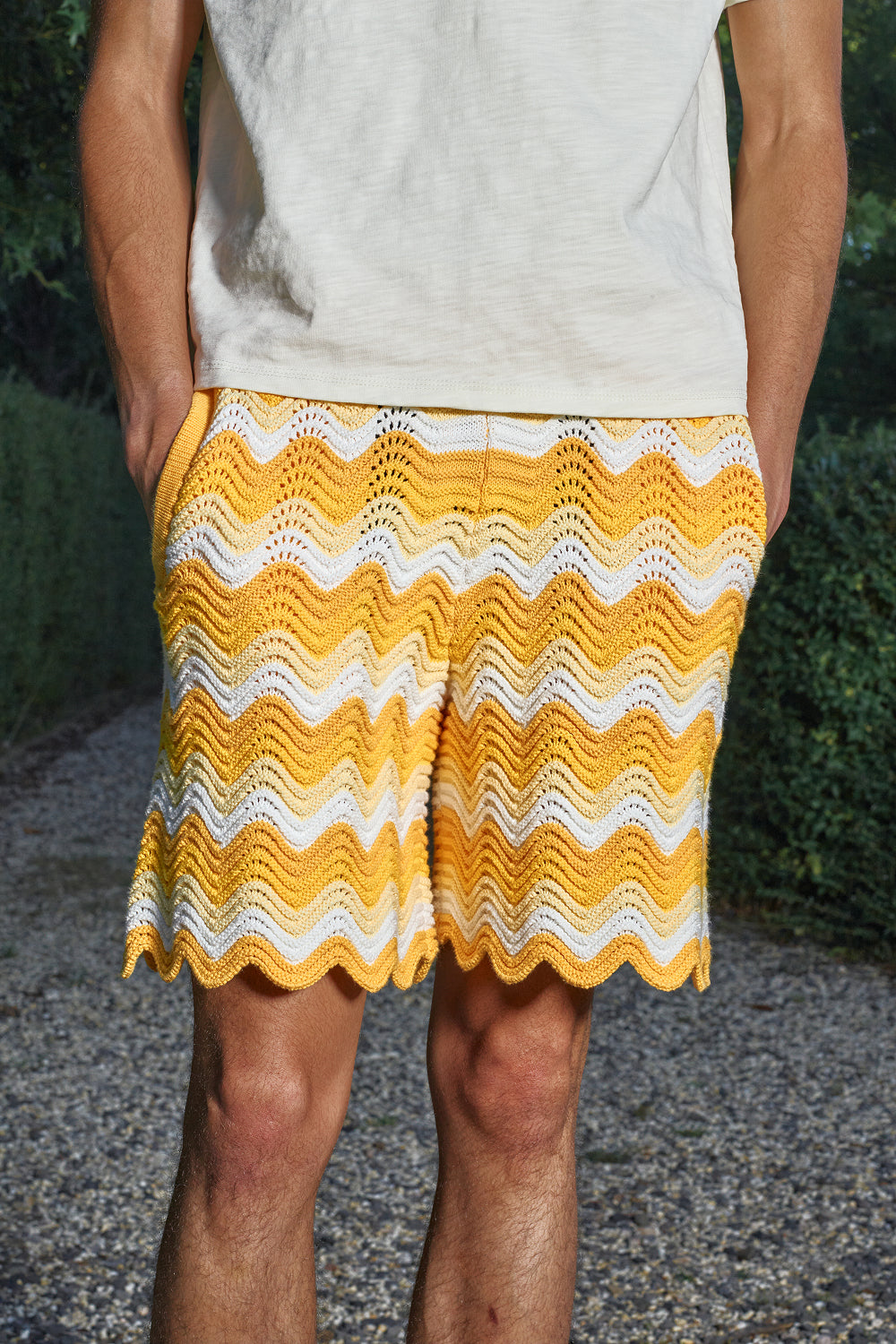 Close-up of model wearing yellow and white shale stitch knit shorts.