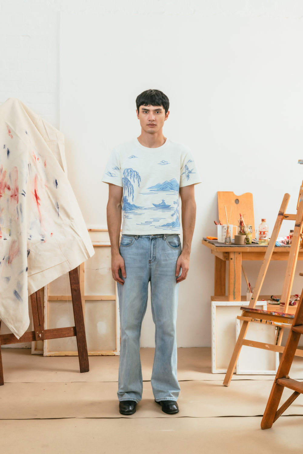 Person wearing a t-shirt with a scenic landscape embroidery in an indoor setting