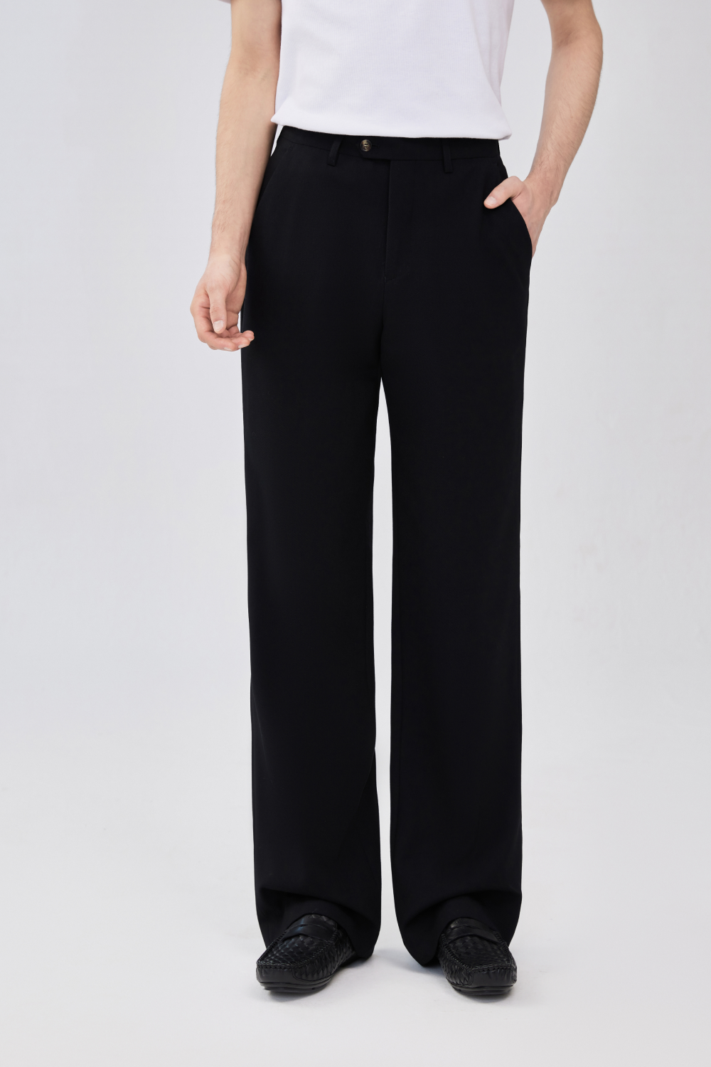 Model wearing black wool trousers with a straight leg, front crease, belt loops, side pockets, and button closure.