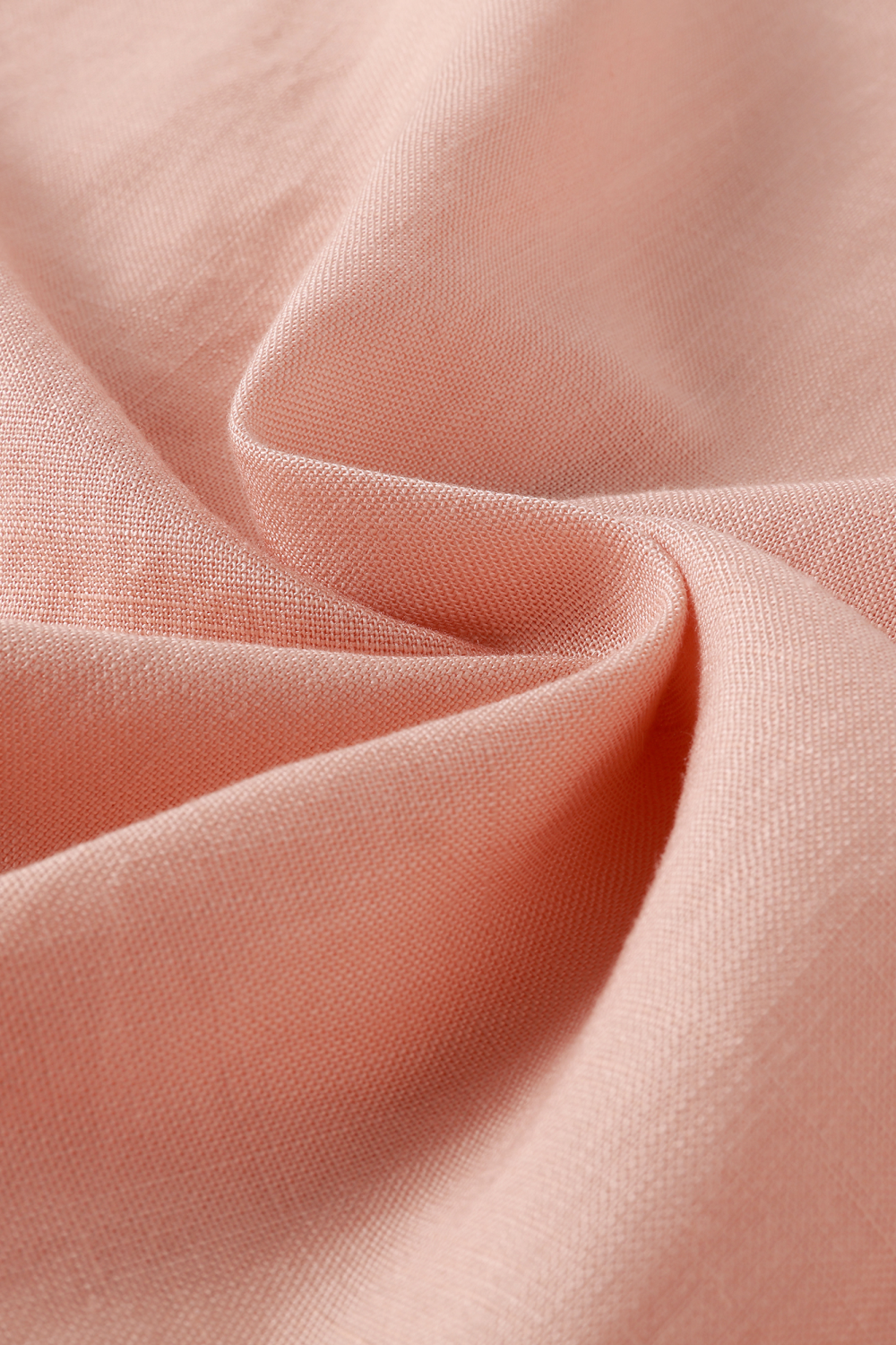 A close-up of draped light pink fabric with soft folds and a fine texture.