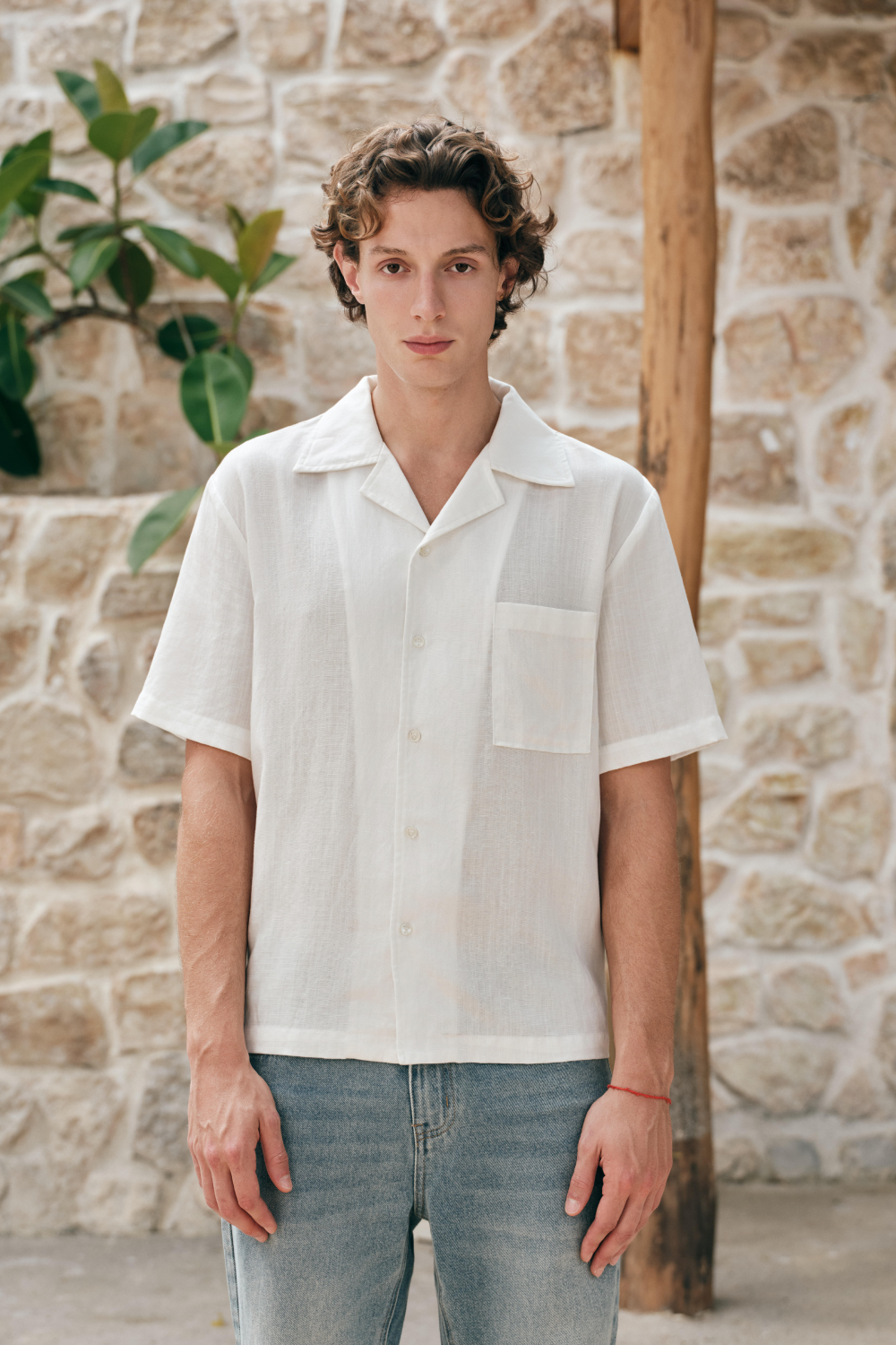 Model wearing a white short-sleeve button-front shirt with an open collar and chest patch pocket.