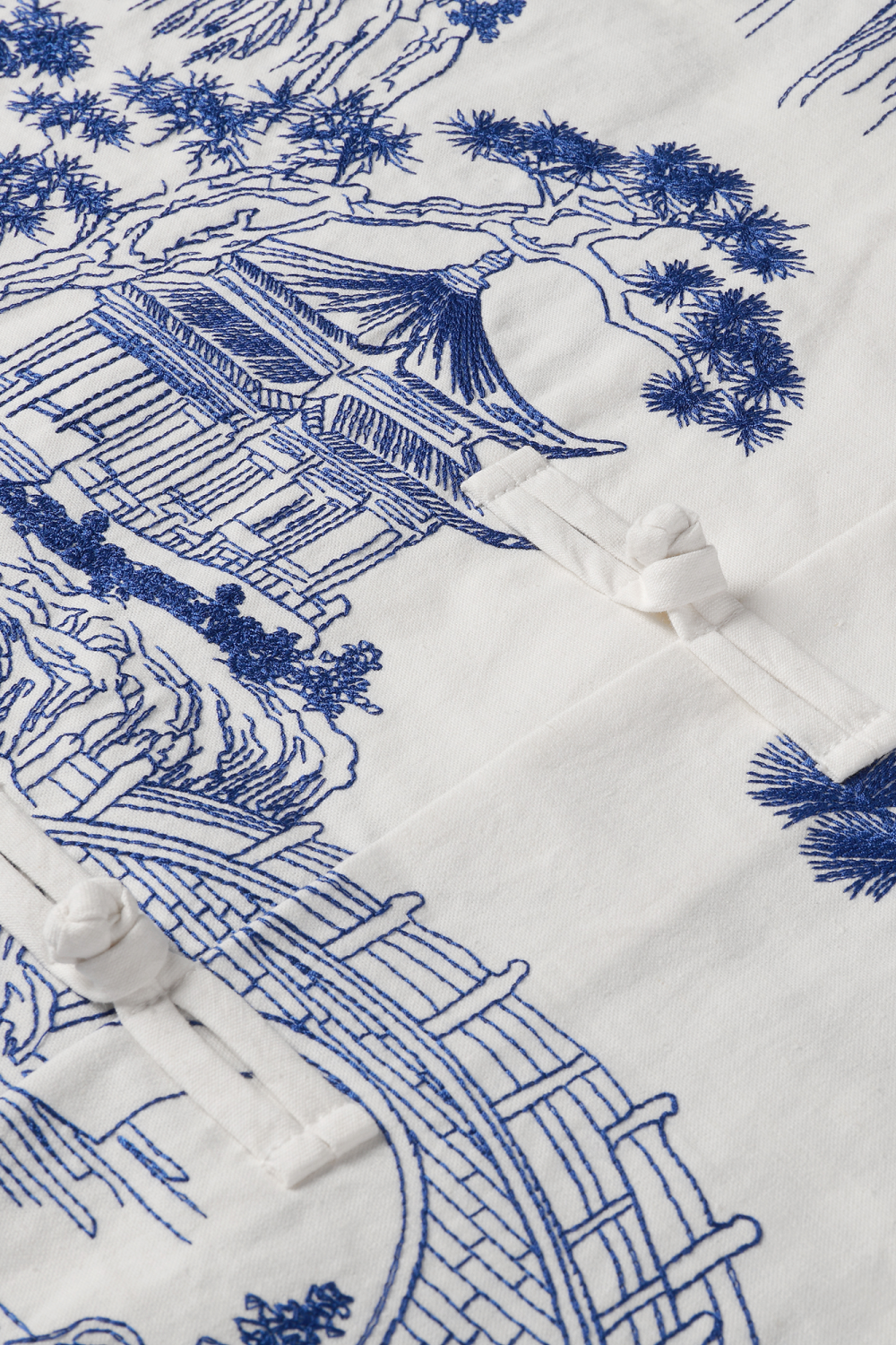 close up of the blue embroidery and the Chinese knot buttons.