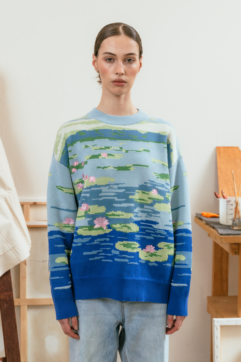 Model wearing a sweater with waterlily design in a room setting